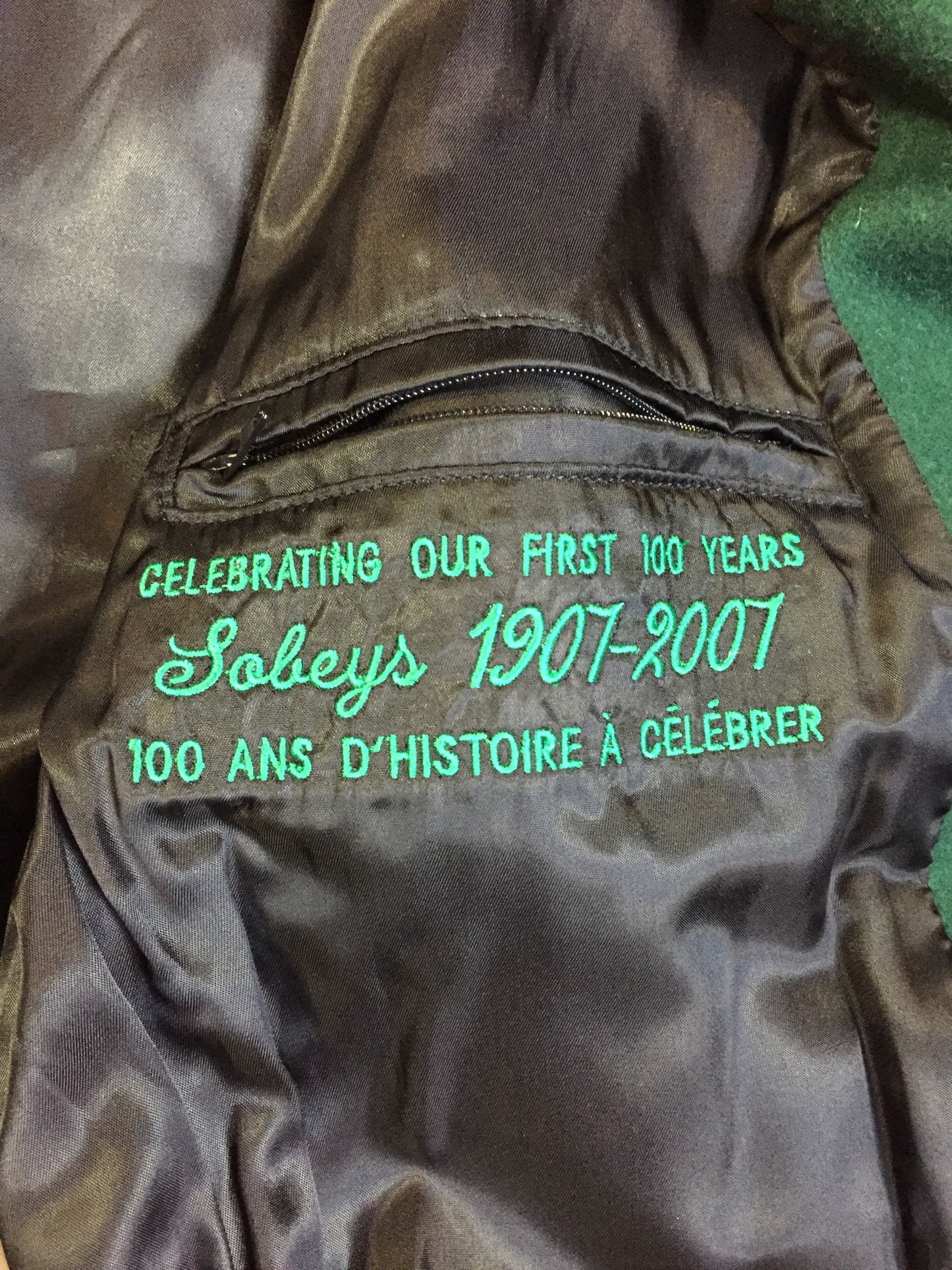 Kingspier Vintage - Roots “Sobey’s Centenary Anniversary” ’07 varsity jacket in green and white with snap closures, slash pockets, knit trim, embroidered “100” emblem on the chest and “07” on the arm.