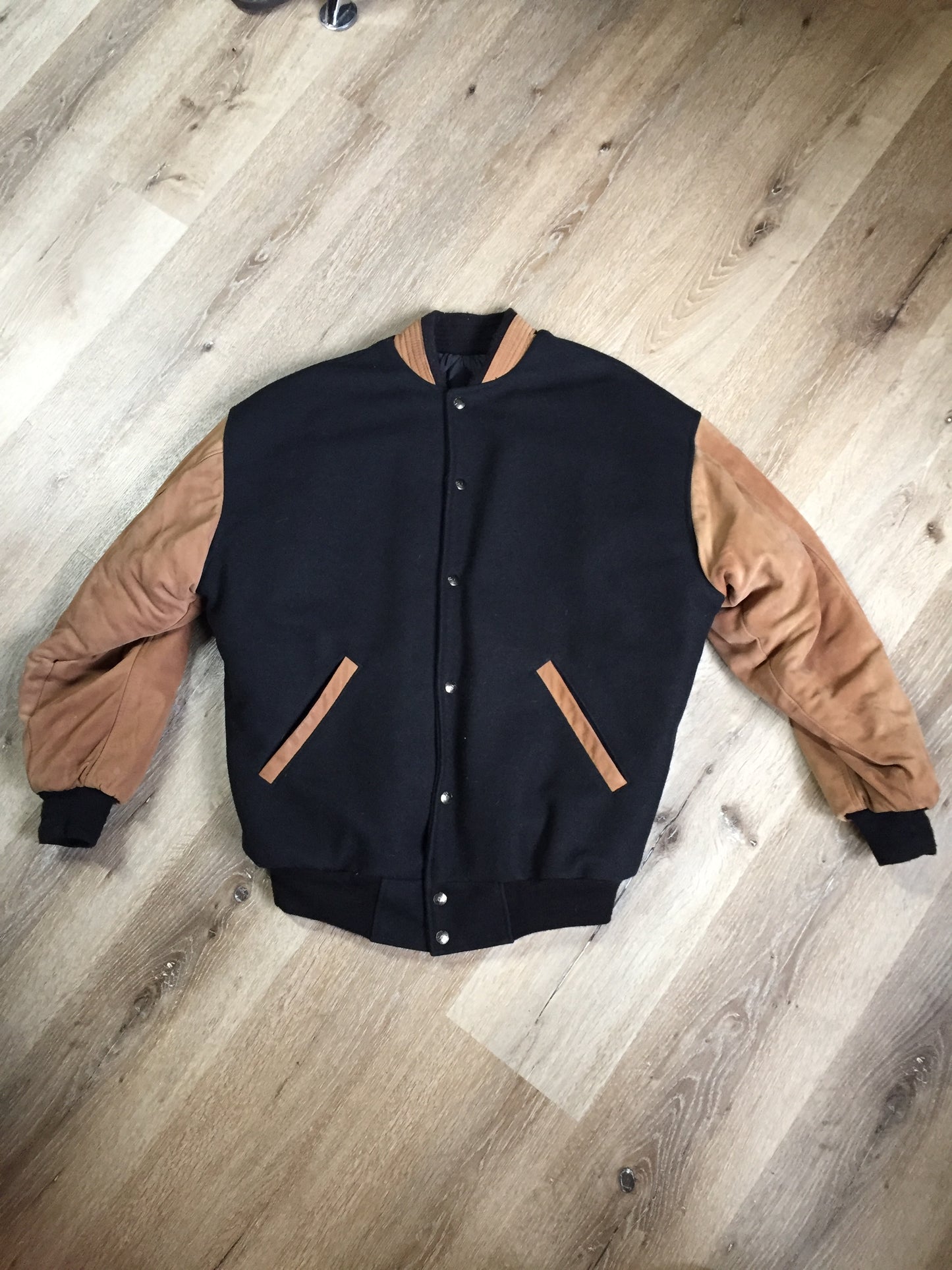 Kingspier Vintage - Trimark black and brown wool/leather varsity jacket with knit trim, snap closures, slash pockets quilted lining and inside pocket. Size large.