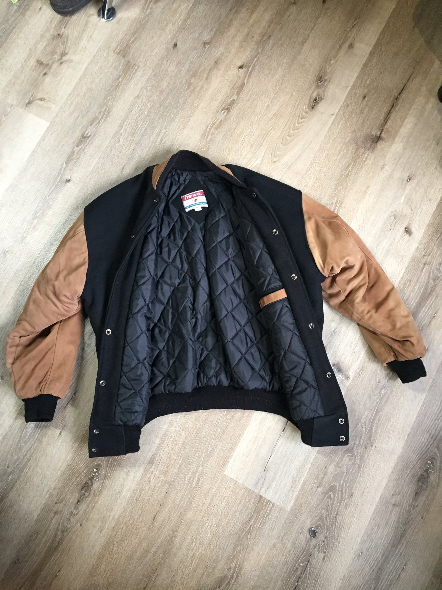 Kingspier Vintage - Trimark black and brown wool/leather varsity jacket with knit trim, snap closures, slash pockets quilted lining and inside pocket. Size large.