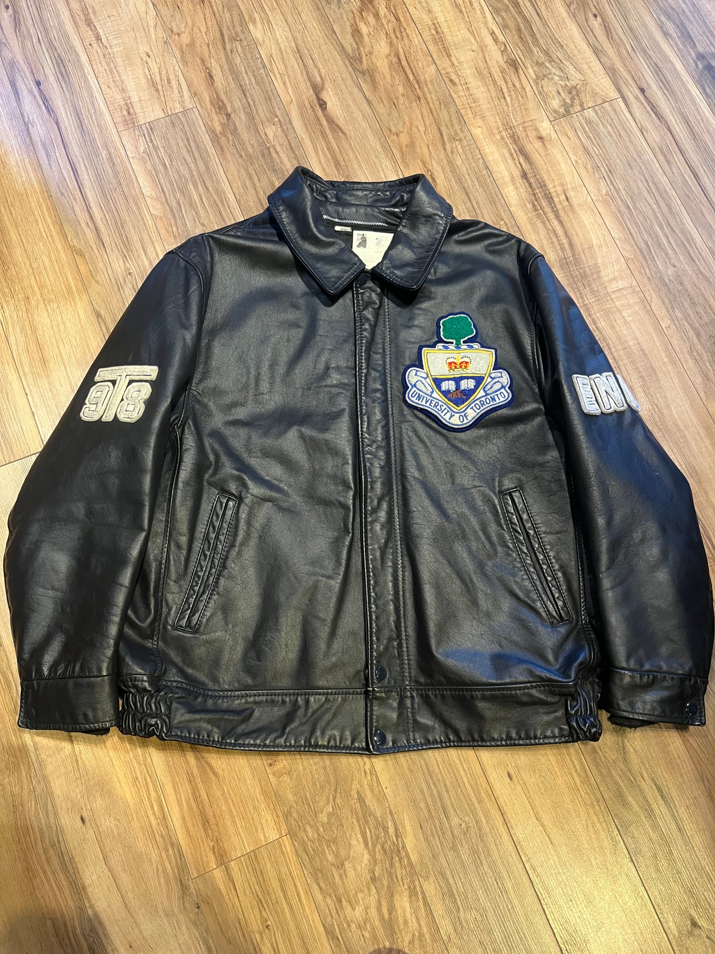 Vintage University of Toronto 1998 English Department Leather Varsity Jacket.
Jacket features embroidered details on the chest, arms and back, two front pockets, zipper and snap closures and a zip out quilted lining.
Size 46.