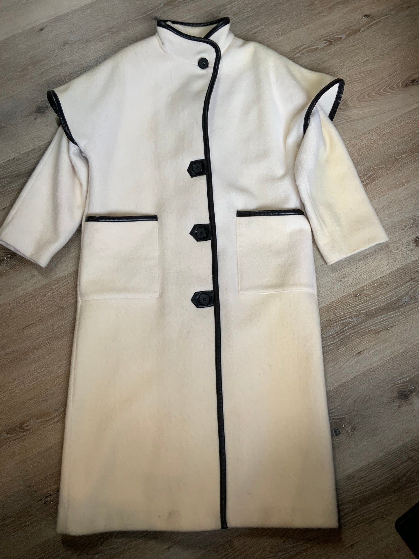 Kingspier Vintage - Genuine Hudson Bay Company 100% virgin wool coat in white with black leather trim, front pockets, flat black buttons and a unique mandarin collar with cape style detail around shoulders. Contains a Hudson’s Bay seal of quality tag. Made in Canada.