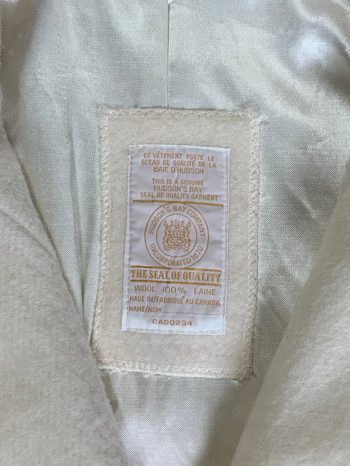 Kingspier Vintage - Genuine Hudson Bay Company 100% virgin wool coat in white with black leather trim, front pockets, flat black buttons and a unique mandarin collar with cape style detail around shoulders. Contains a Hudson’s Bay seal of quality tag. Made in Canada.