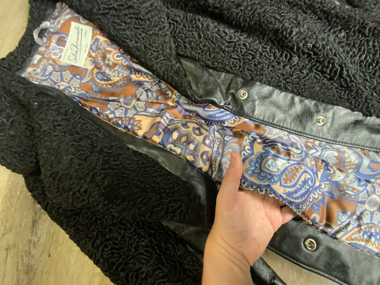 Kingspier Vintage - Salon Fernande Furs black persian wool coat with black leather trim details, four button closures down the front pockets and striking blue and bronze paisley lining with inside pockets. Made in Montreal.
