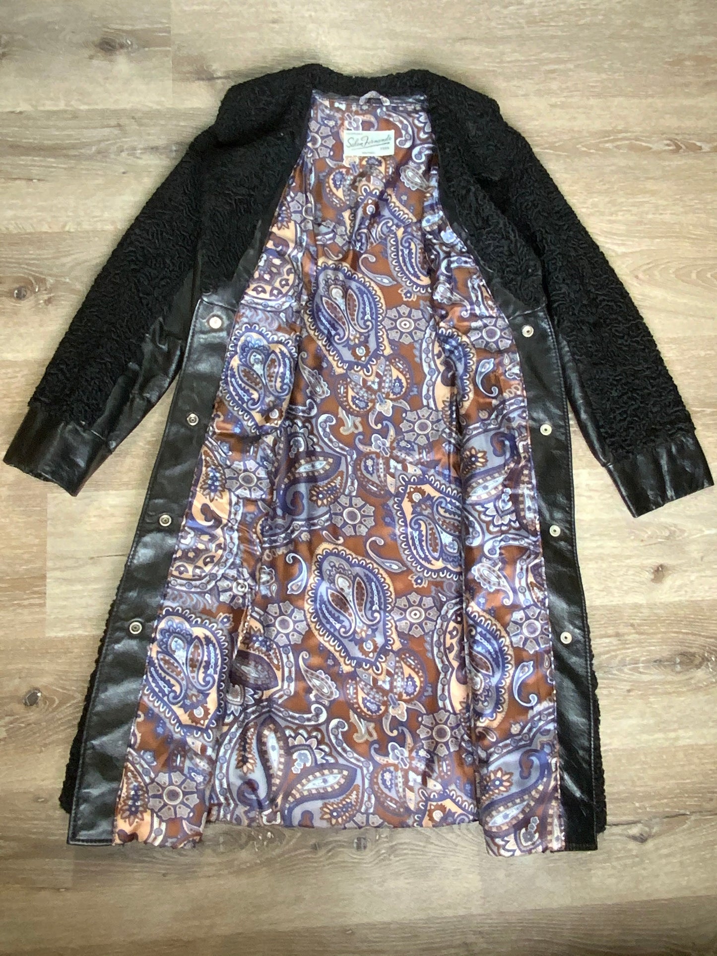 Kingspier Vintage - Salon Fernande Furs black persian wool coat with black leather trim details, four button closures down the front pockets and striking blue and bronze paisley lining with inside pockets. Made in Montreal.