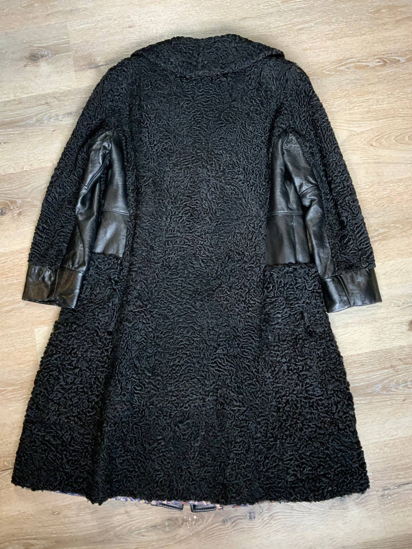 Kingspier Vintage - Salon Fernande Furs black persian wool coat with black leather trim details, four button closures down the front pockets and striking blue and bronze paisley lining with inside pockets. Made in Montreal.