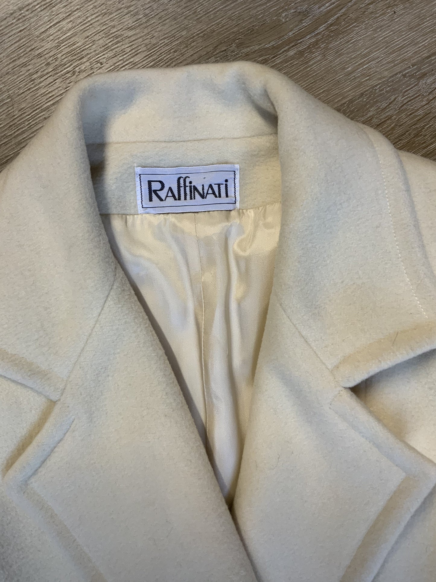 Kingspier Vintage - Raffinati 1980’s double breasted wool blend coat in cream. This coat features unique gold buttons in front, front pockets and a belt in the back. Fits a size 8.