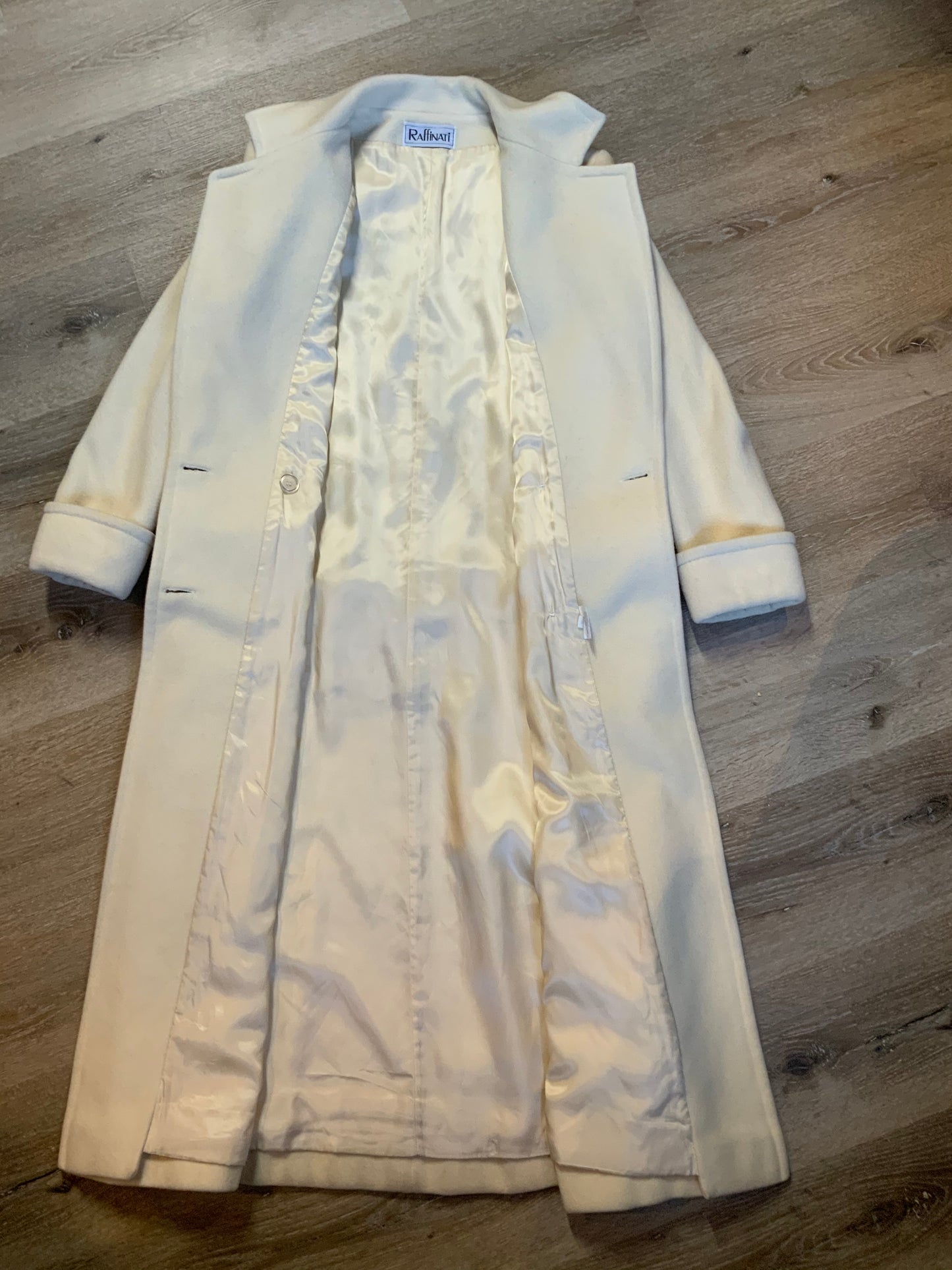 Kingspier Vintage - Raffinati 1980’s double breasted wool blend coat in cream. This coat features unique gold buttons in front, front pockets and a belt in the back. Fits a size 8.