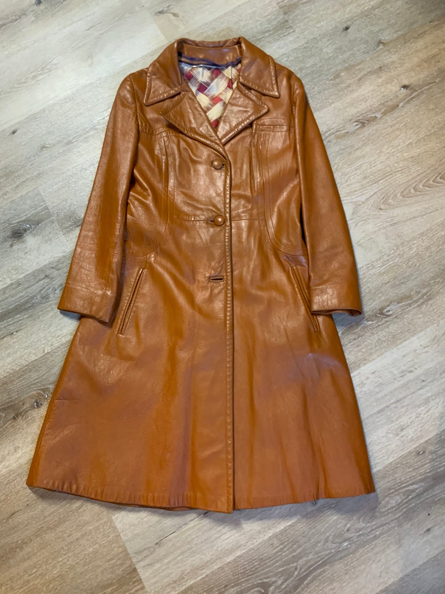 Kingspier Vintage - Form fitting 1970’s full length caramel brown leather coat with buttons down the front and a fun woven motif lining.
