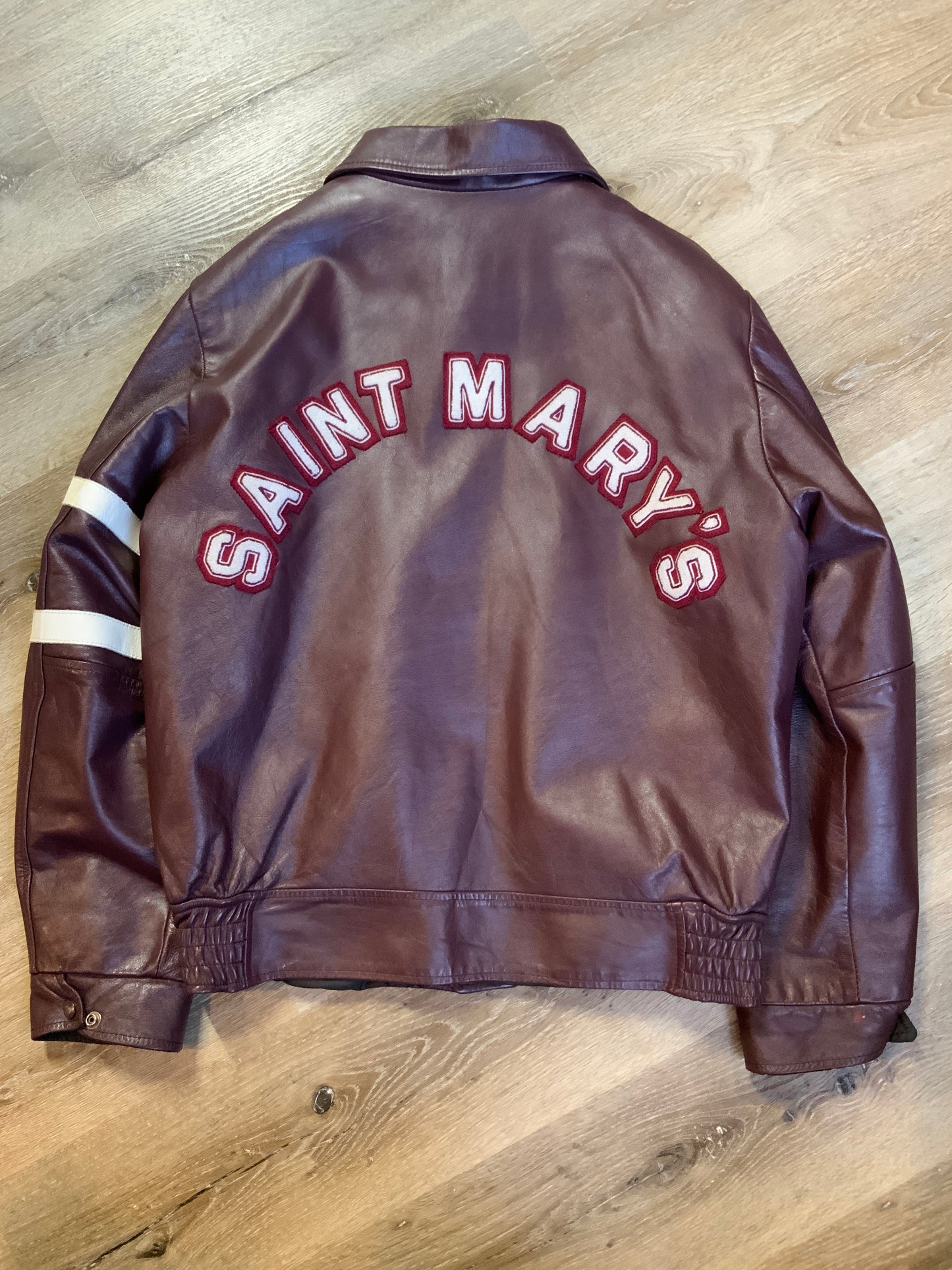 Kingspier Vintage - Saint Mary’s Letterman Jacket in Burgundy with “Saint Mary’s” written across the back, snap closures, slash buttons, zip out lining and inside pocket. Made in Canada. Size 44.