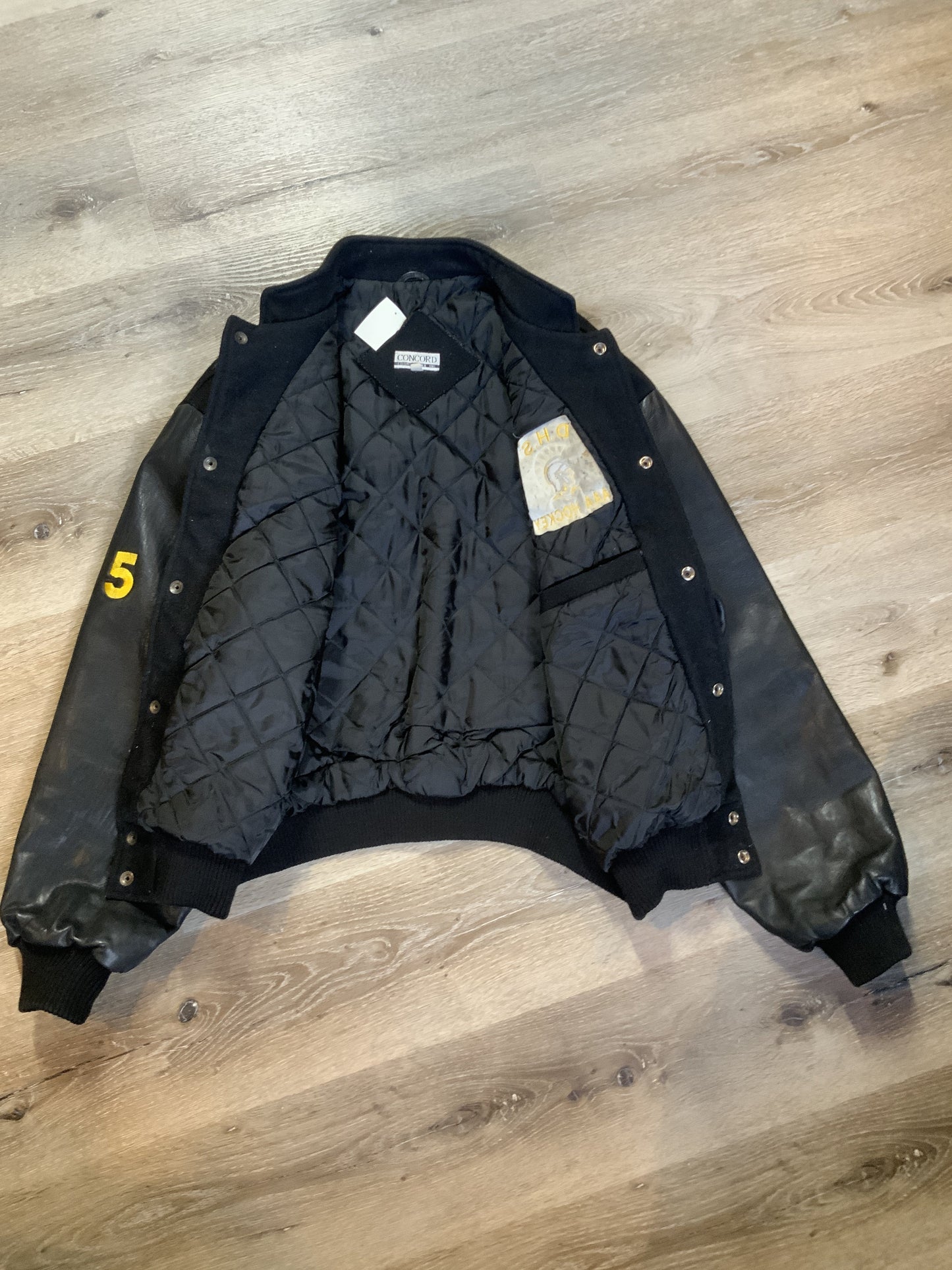 Kingspier Vintage - Dartmouth High School AAA Hockey letterman’s jacket in black with snap closures, slash pockets, quilted lining and embroidered team emblem. Made in Canada. Size XL.