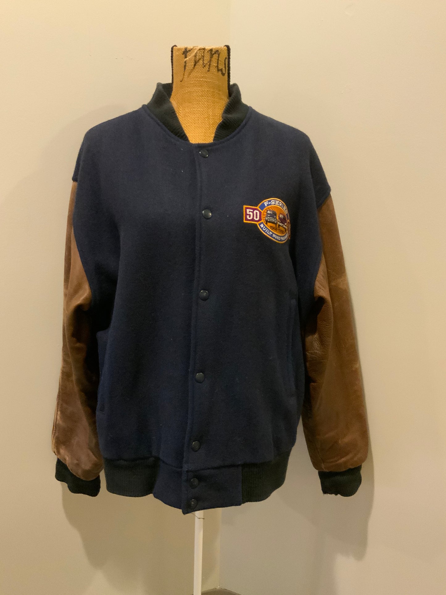 Kingspier Vintage - Ford F-Series 50 year anniversary letterman’s jacket in navy with brown leather sleeves, snap closures, slash pockets and an inside pocket.