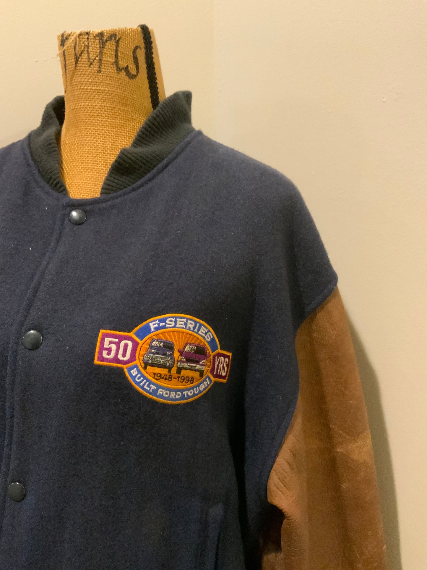 Kingspier Vintage - Ford F-Series 50 year anniversary letterman’s jacket in navy with brown leather sleeves, snap closures, slash pockets and an inside pocket.