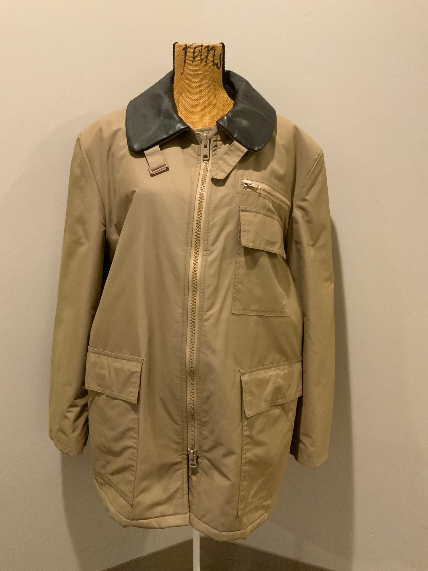 Kingspier Vintage - Special Reserve hunting jacket in beige with brown leather collar featuring a strap to keep your collar in place, zipper, three flap pockets and one zip pocket. Knit inside cuffs. lined for cooler weather with drawstring at waist. Made in Canada. Size 44.