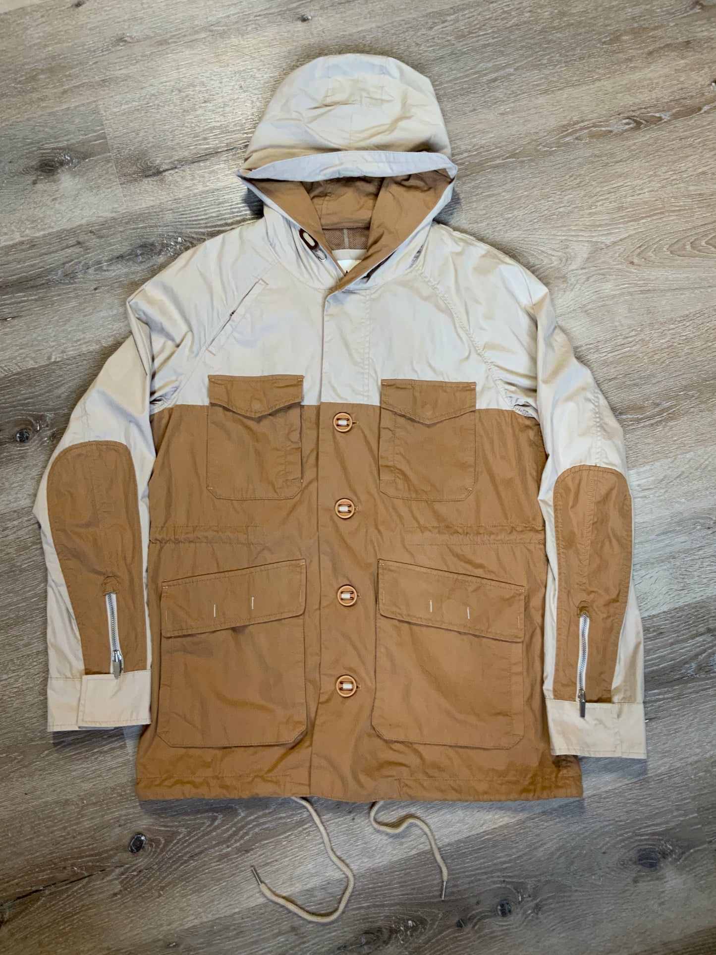 Kingspier Vintage - Tate beige and tan field jacket with hood, button closures, flap pockets, vent in the back, elbow patches and drawstring at the waist and the bottom hem.