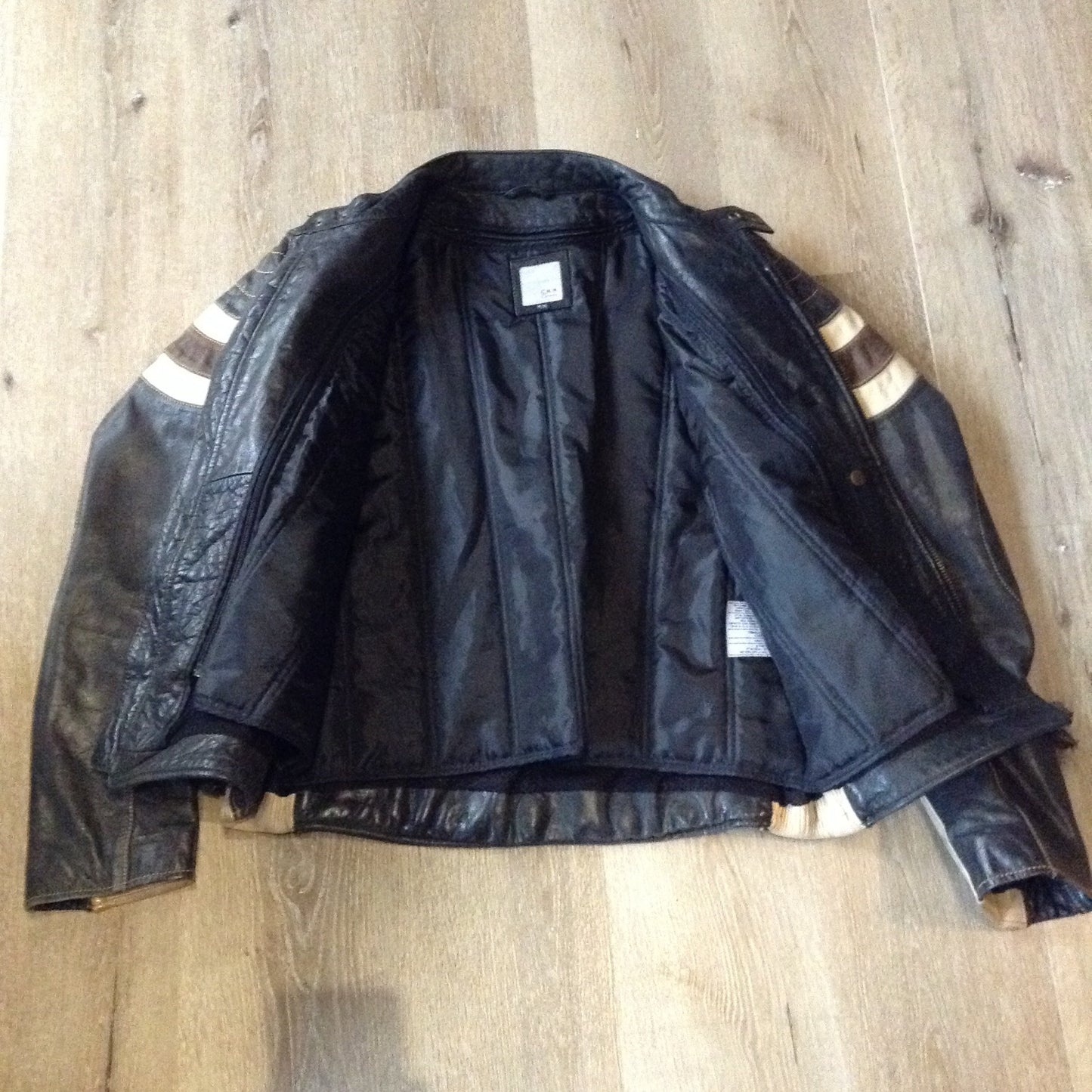 Kingspier Vintage -Vintage CCM Canada black, white and brown leather moto jacket with zipper closure, pockets and a snap collar. Size XL.