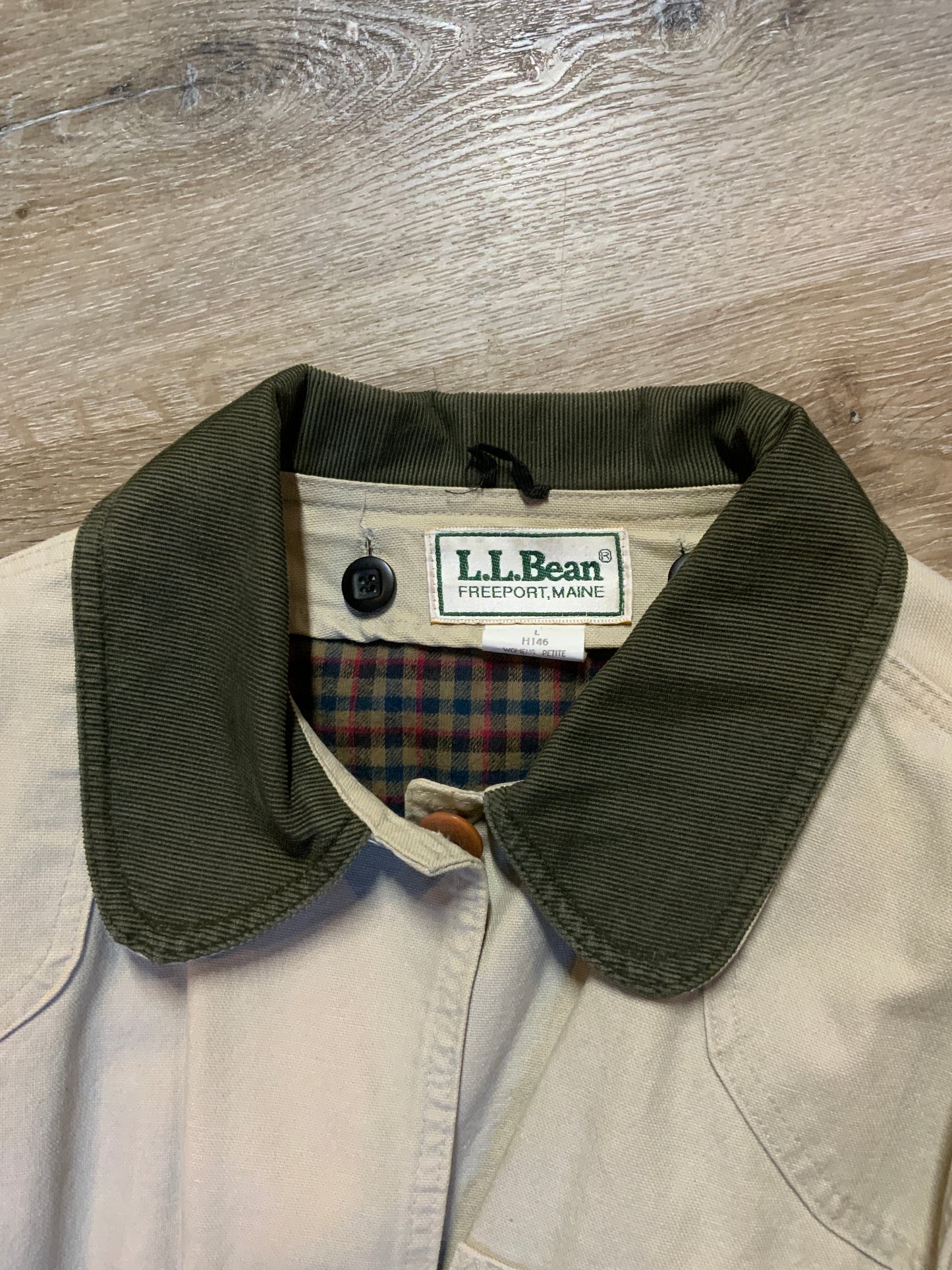 Kingspier Vintage - L.L.Bean beige field jacket with green corduroy collar and cuff, four front patch pockets and one zip pocket, button closures, removable plaid "Prima Loft" synthetic down lining. Size large petite women’s.