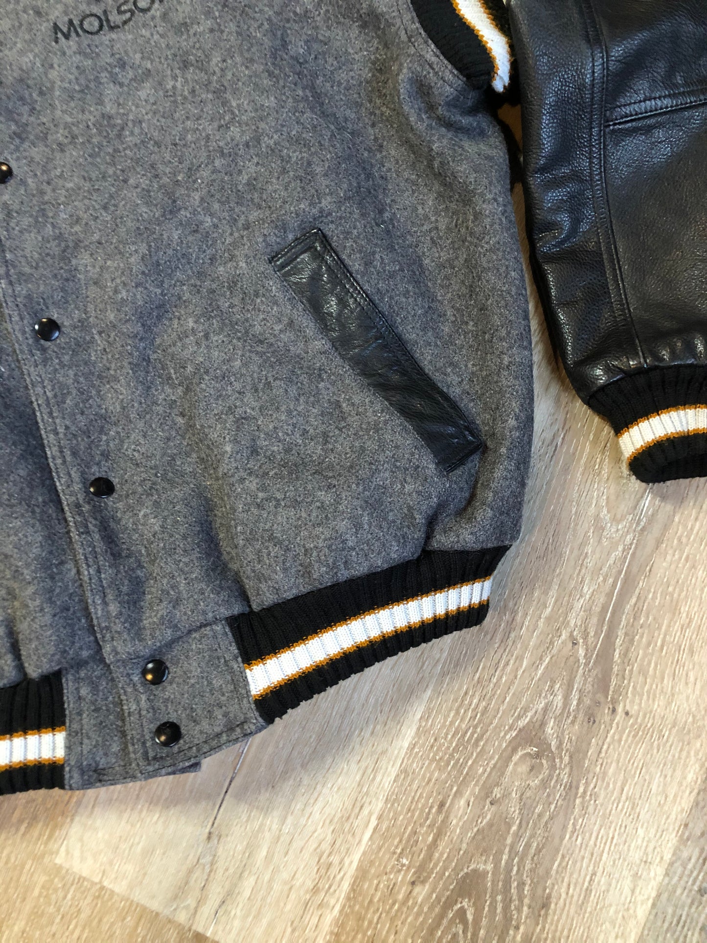 Kingspier Vintage - Fat Cat by Jazz grey and black wool varsity jacket with two large custom Jazz Golf embroidered patches on the arm and the back and Molson is embroidered on the chest in black, leather sleeves and collar, pockets, snap closures, knit details and a quilted lining. Made in Canada by Mondetta . Size XL.