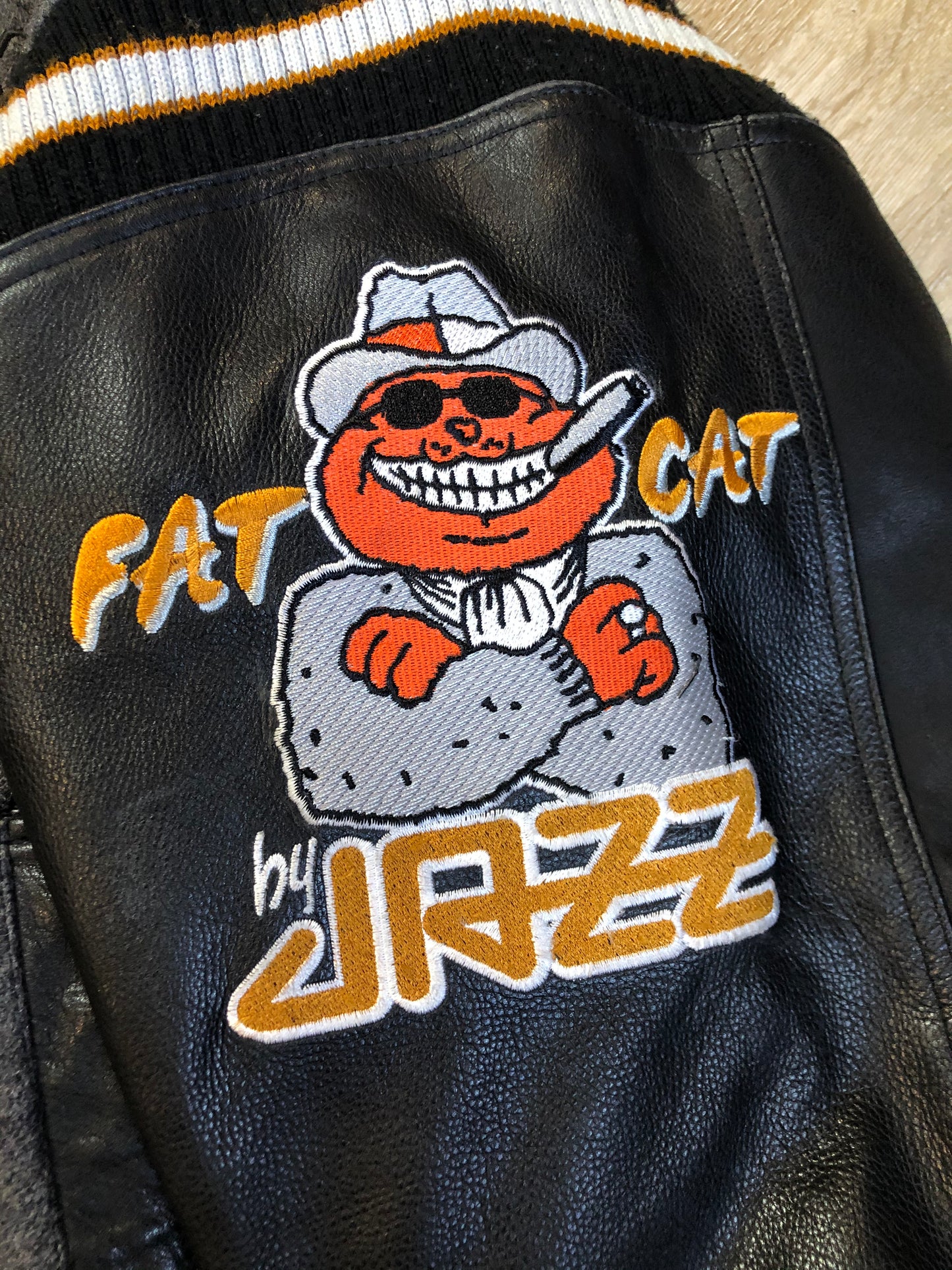 Kingspier Vintage - Fat Cat by Jazz grey and black wool varsity jacket with two large custom Jazz Golf embroidered patches on the arm and the back and Molson is embroidered on the chest in black, leather sleeves and collar, pockets, snap closures, knit details and a quilted lining. Made in Canada by Mondetta . Size XL.
