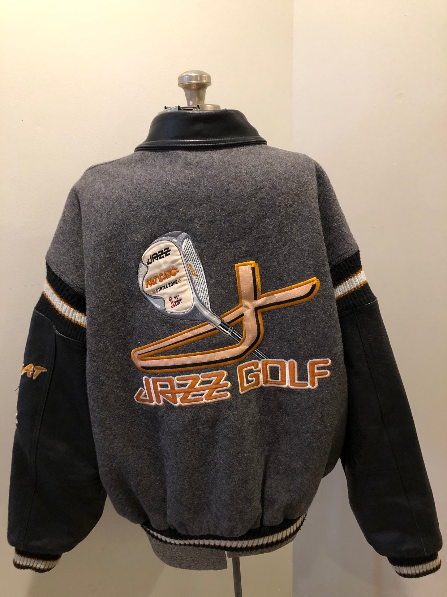 Kingspier Vintage - Fat Cat by Jazz grey and black wool varsity jacket with two large custom Jazz Golf embroidered patches on the arm and the back and Molson is embroidered on the chest in black, leather sleeves and collar, pockets, snap closures, knit details and a quilted lining. Made in Canada by Mondetta . Size XL.