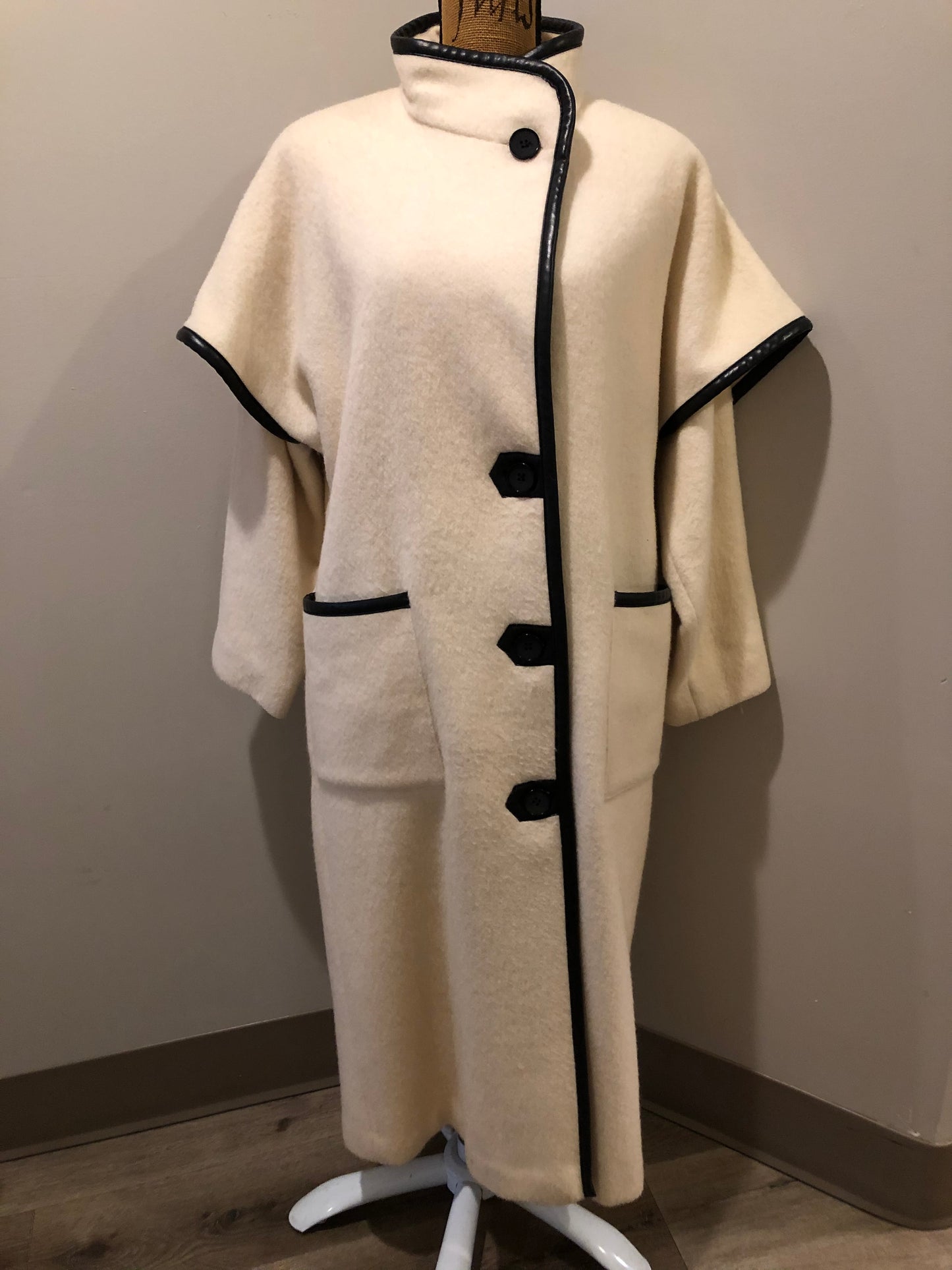 Kingspier Vintage - Genuine Hudson Bay Company 100% virgin wool coat in white with black leather trim, front pockets, flat black buttons and a unique mandarin collar with cape style detail around shoulders. Contains a Hudson’s Bay seal of quality tag. Made in Canada.