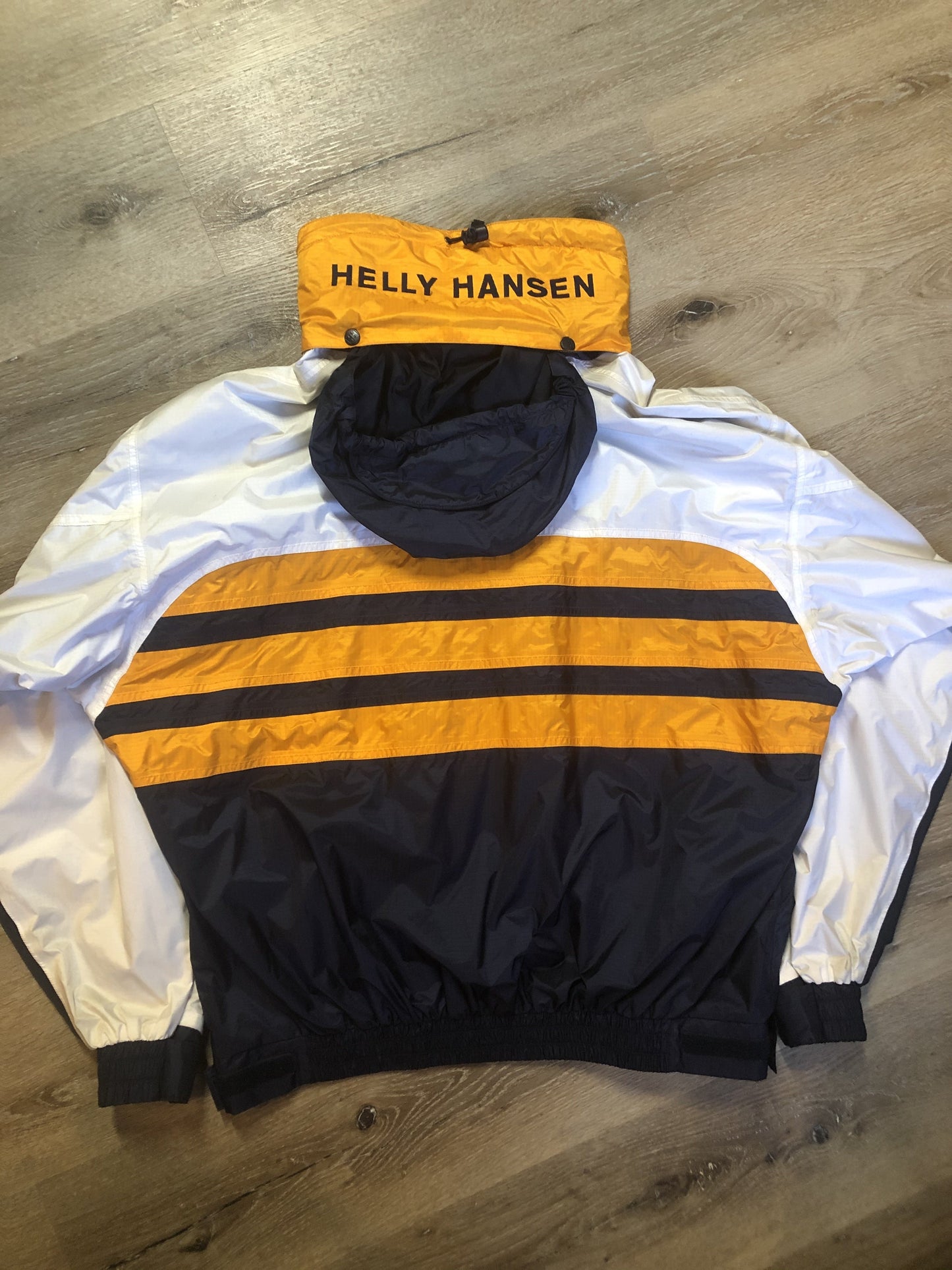 Kingspier Vintage - Heely Hansen ”Extreme” white,yellow and navy windbreaker with funnel neck and roll up hood, zipper and Velcro closures, reflective square on front and Helly Hansen patch on arm. Size XL.