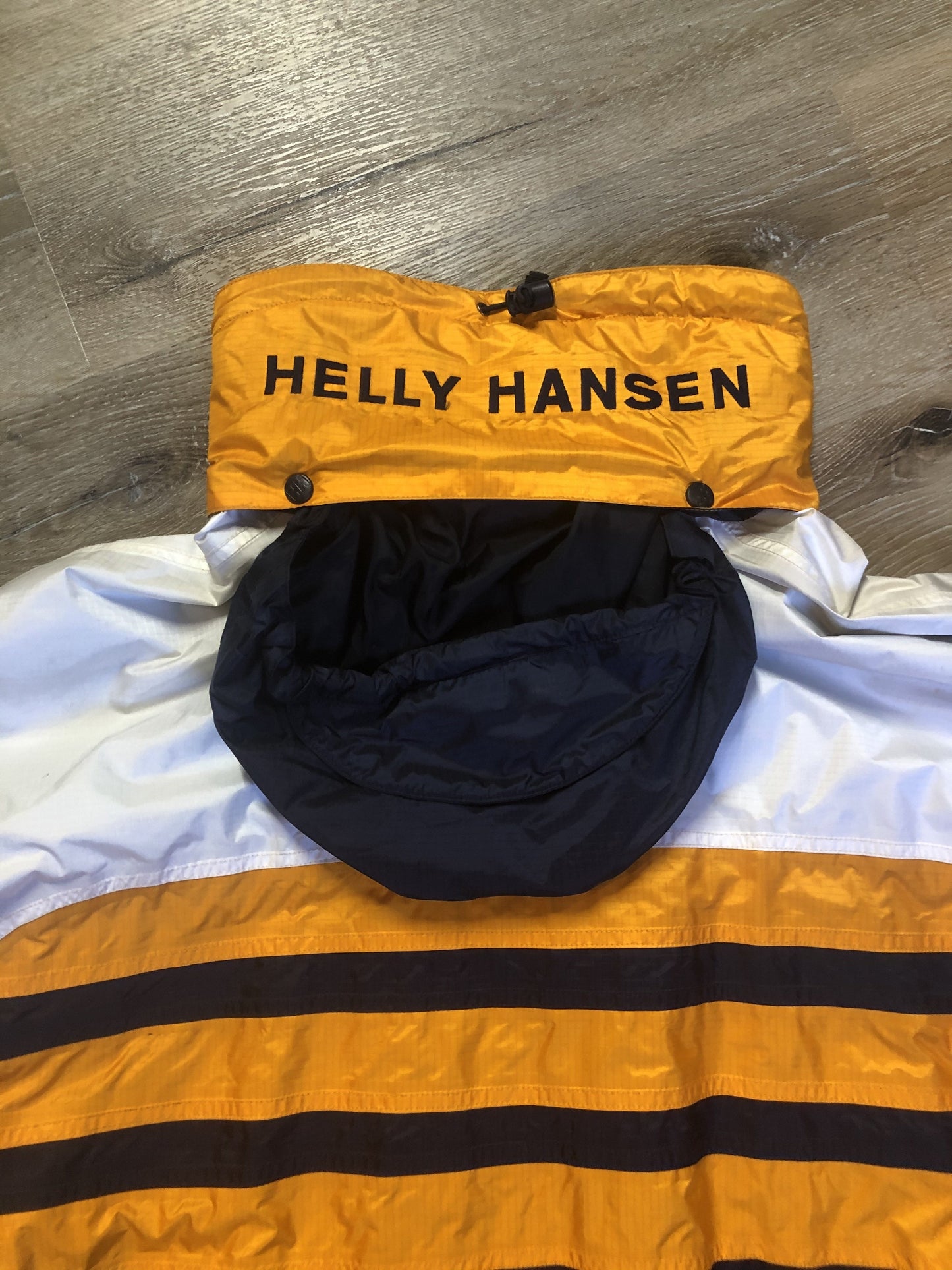 Kingspier Vintage - Heely Hansen ”Extreme” white,yellow and navy windbreaker with funnel neck and roll up hood, zipper and Velcro closures, reflective square on front and Helly Hansen patch on arm. Size XL.