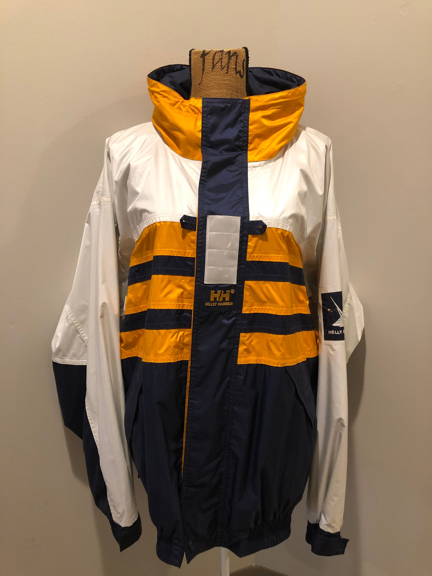 Kingspier Vintage - Heely Hansen ”Extreme” white,yellow and navy windbreaker with funnel neck and roll up hood, zipper and Velcro closures, reflective square on front and Helly Hansen patch on arm. Size XL.