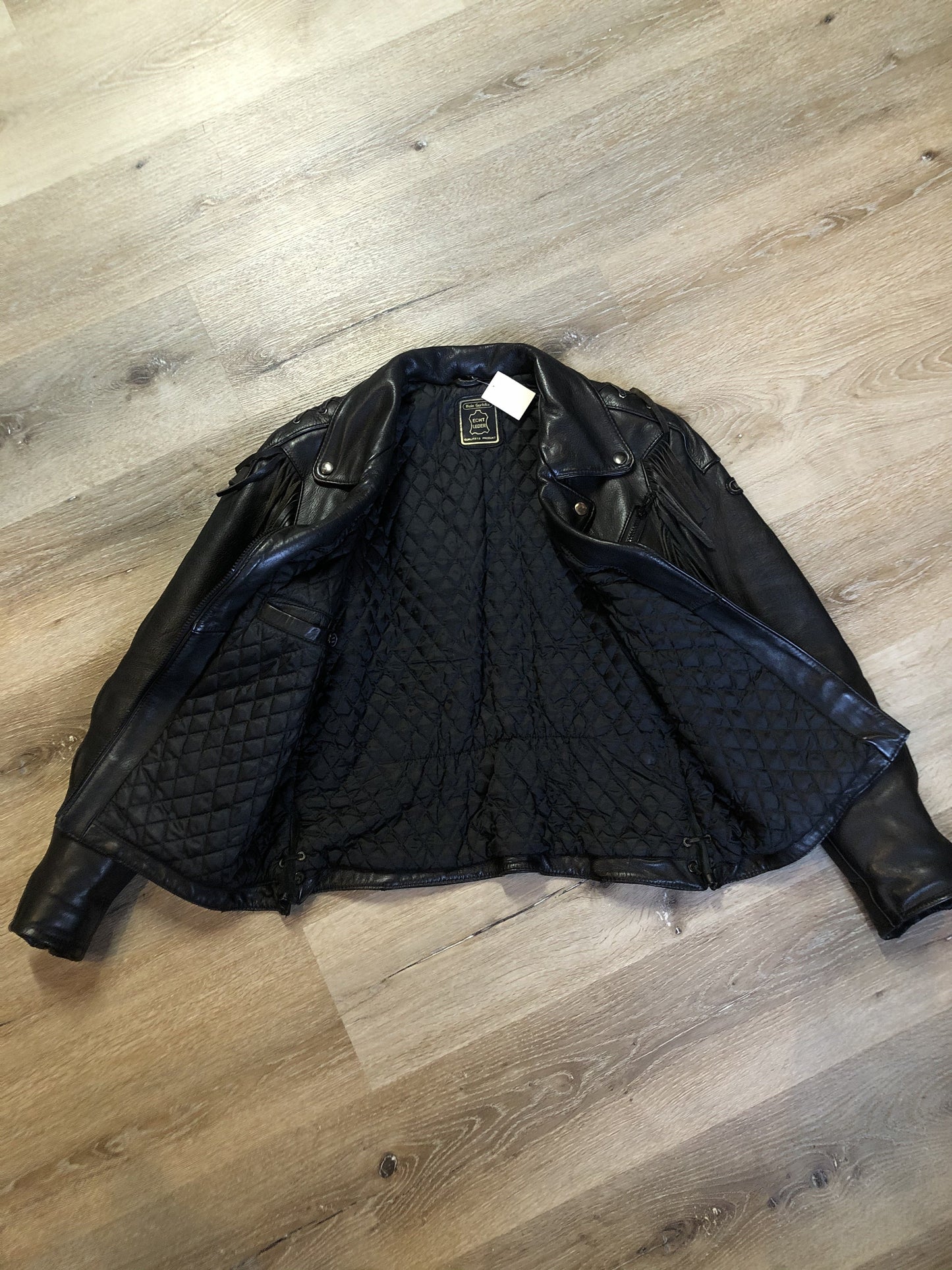 Kingspier Vintage - Hein Gericks black leather motorcycle jacket with fringe detail, zipper, vertical zip pockets lace-up shoulder detail, a quilted lining with inside pocket. Fits Small.