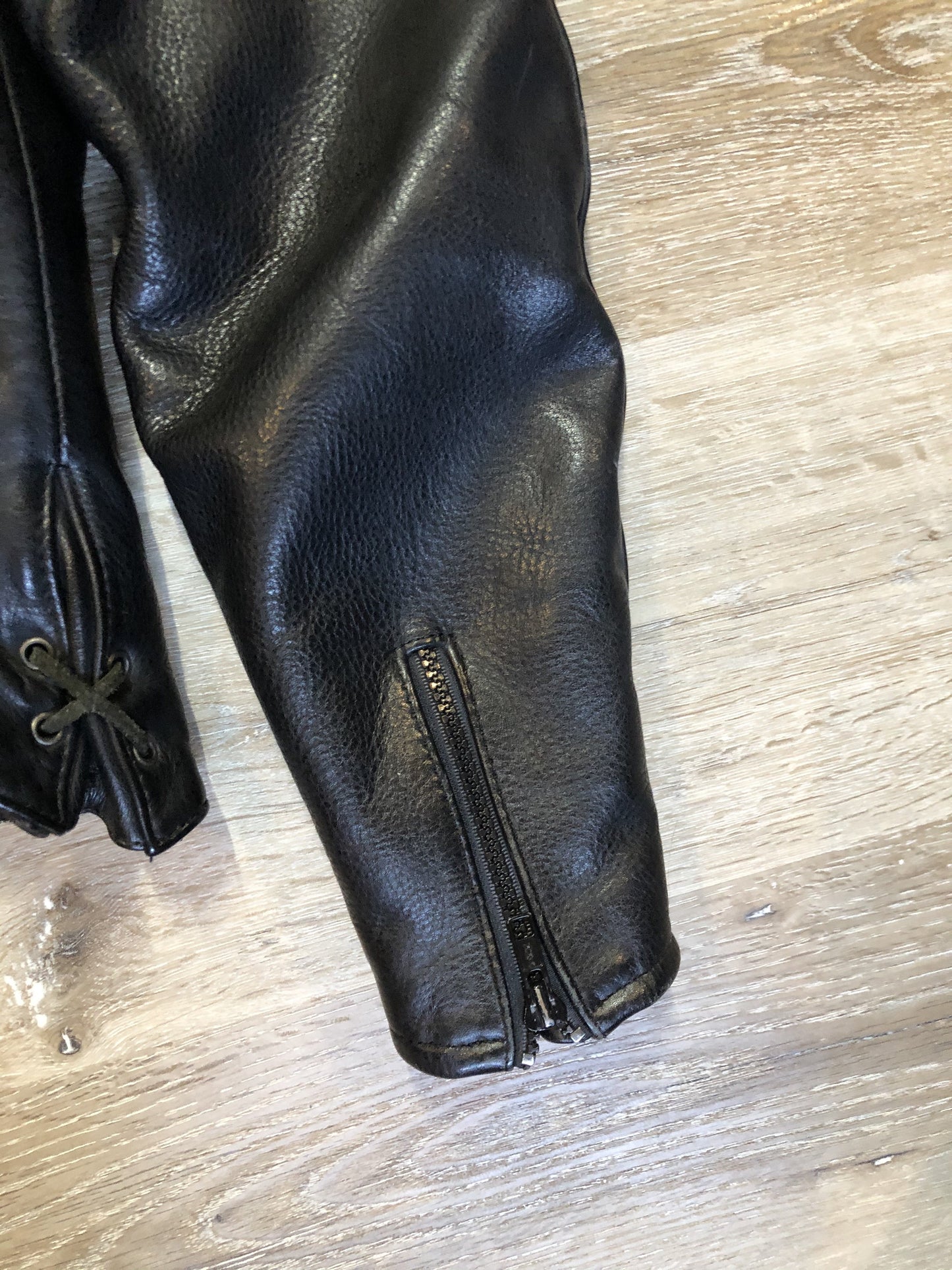 Kingspier Vintage - Hein Gericks black leather motorcycle jacket with fringe detail, zipper, vertical zip pockets lace-up shoulder detail, a quilted lining with inside pocket. Fits Small.