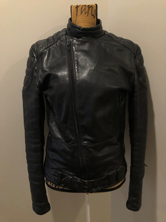 Kingspier Vintage - Taurus by Drospo black leather moto jacket with stretch detailing on the sides and a belt at the waist, zipper down the front, standing collar with Velcro strap, slash pockets and a quilted lining with inside pocket. Size 38. Made in Canada.
