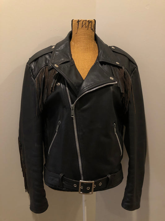 Kingspier Vintage - Action black leather motorcycle jacket with fringe detail and belt at waist. Zipper closure and zip slash pockets, quilted lining with inside pocket. Made in Canada. Size 40.