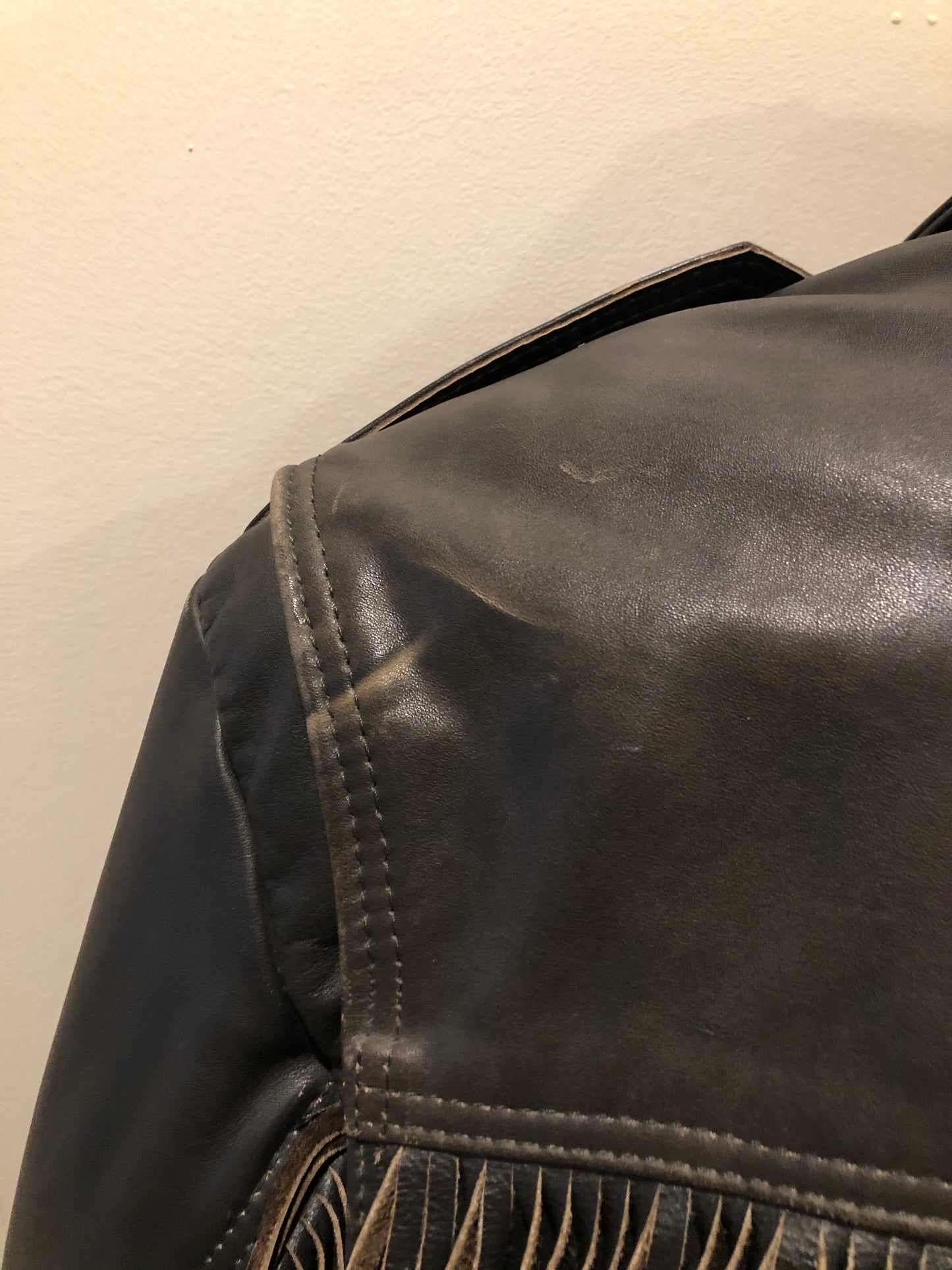 Kingspier Vintage - Action black leather motorcycle jacket with fringe detail and belt at waist. Zipper closure and zip slash pockets, quilted lining with inside pocket. Made in Canada. Size 40.