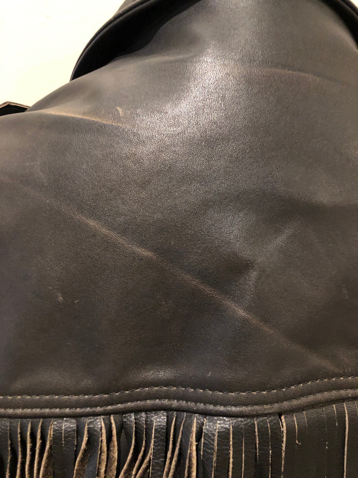 Kingspier Vintage - Action black leather motorcycle jacket with fringe detail and belt at waist. Zipper closure and zip slash pockets, quilted lining with inside pocket. Made in Canada. Size 40.
