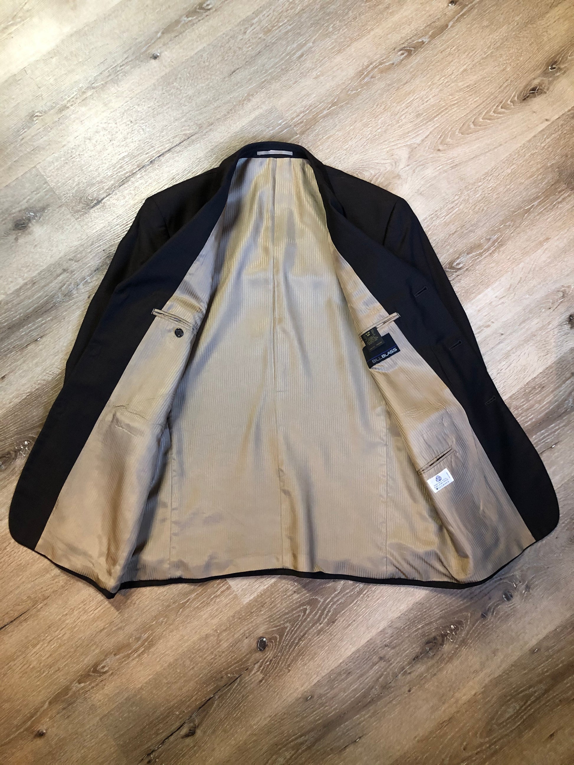 Kingspier Vintage - Bill Blass dark brown 100% pure wool two piece suit. The jacket is a single breasted three button notch lapel with two flap pockets and a beige lining with two inside pockets, Pants are pleated with welt pockets.