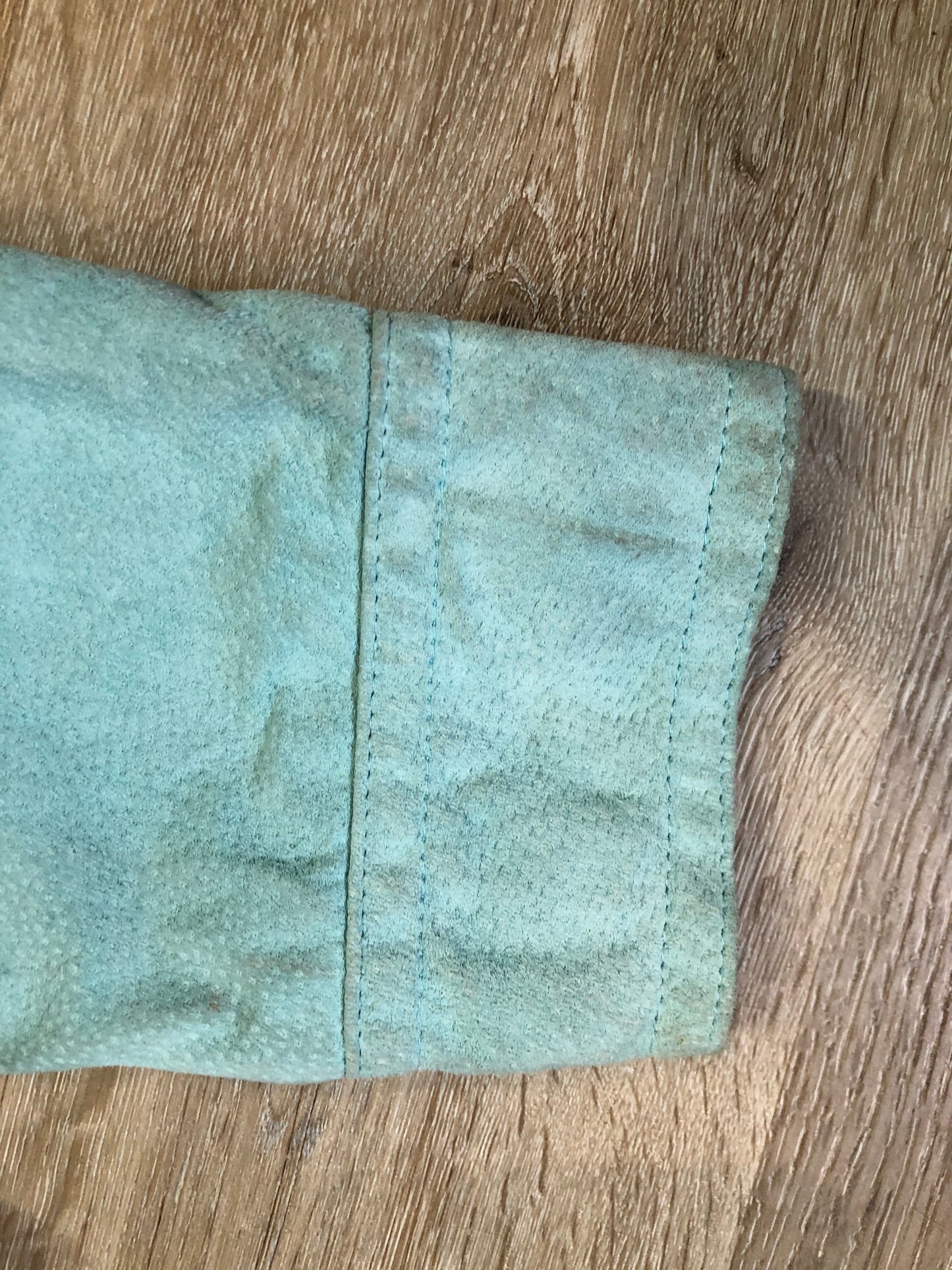 Kingspier Vintage - LAL “Live A LIttle” light teal suede jacket with hidden hook closures, brass grommets running down the front, two zip slash pockets and a small belt at the back. Size large.