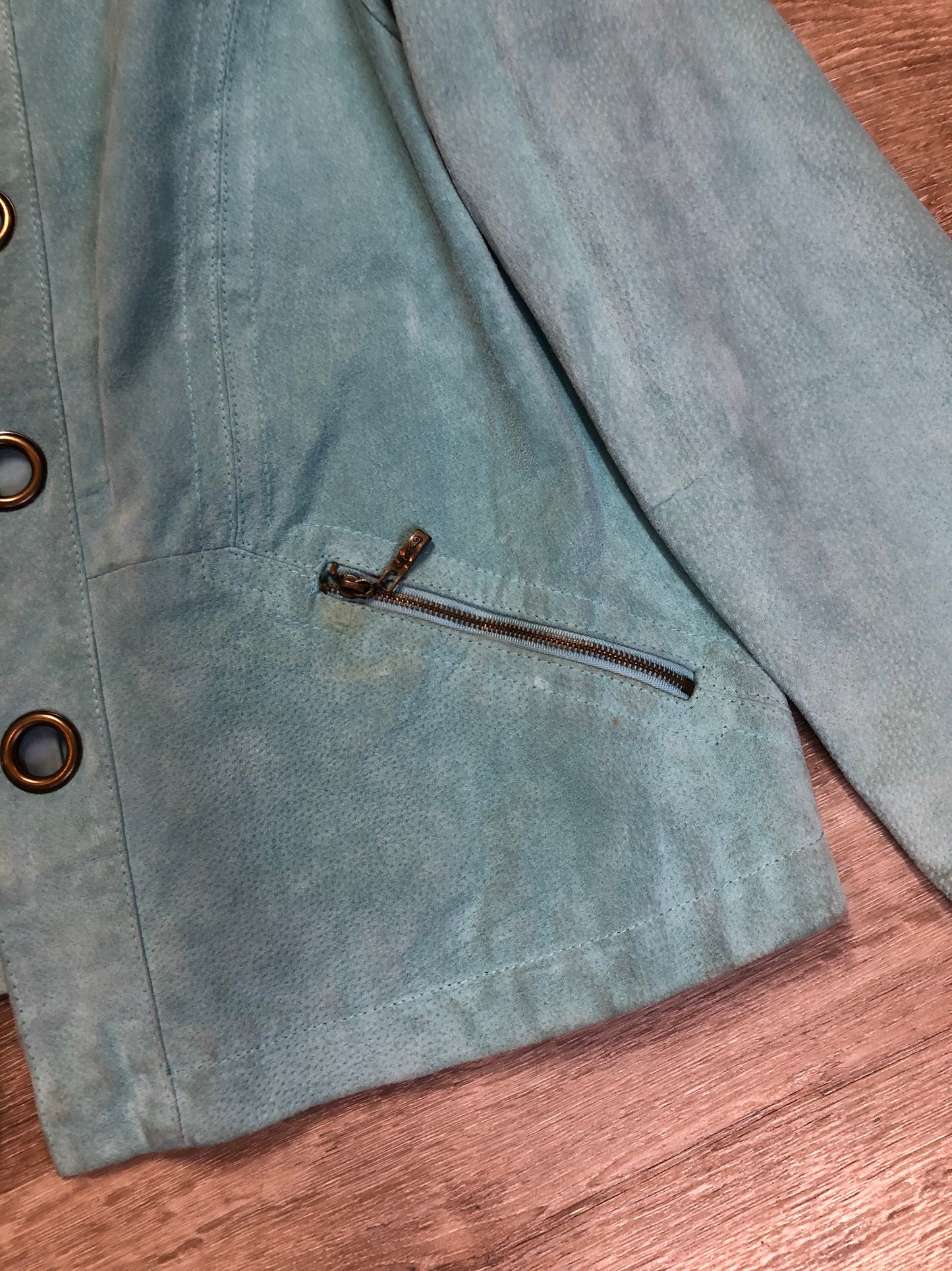 Kingspier Vintage - LAL “Live A LIttle” light teal suede jacket with hidden hook closures, brass grommets running down the front, two zip slash pockets and a small belt at the back. Size large.