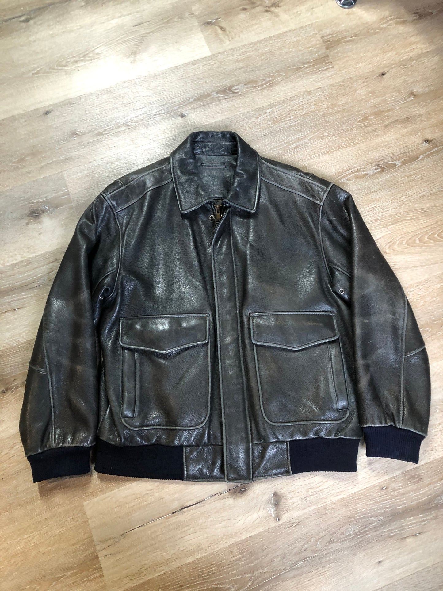 Kingspier Vintage - Black leather pilot jacket with zipper and snap closures, flap pockets, knit trim, inside pocket and plane pattern on inside lining. Size large.
