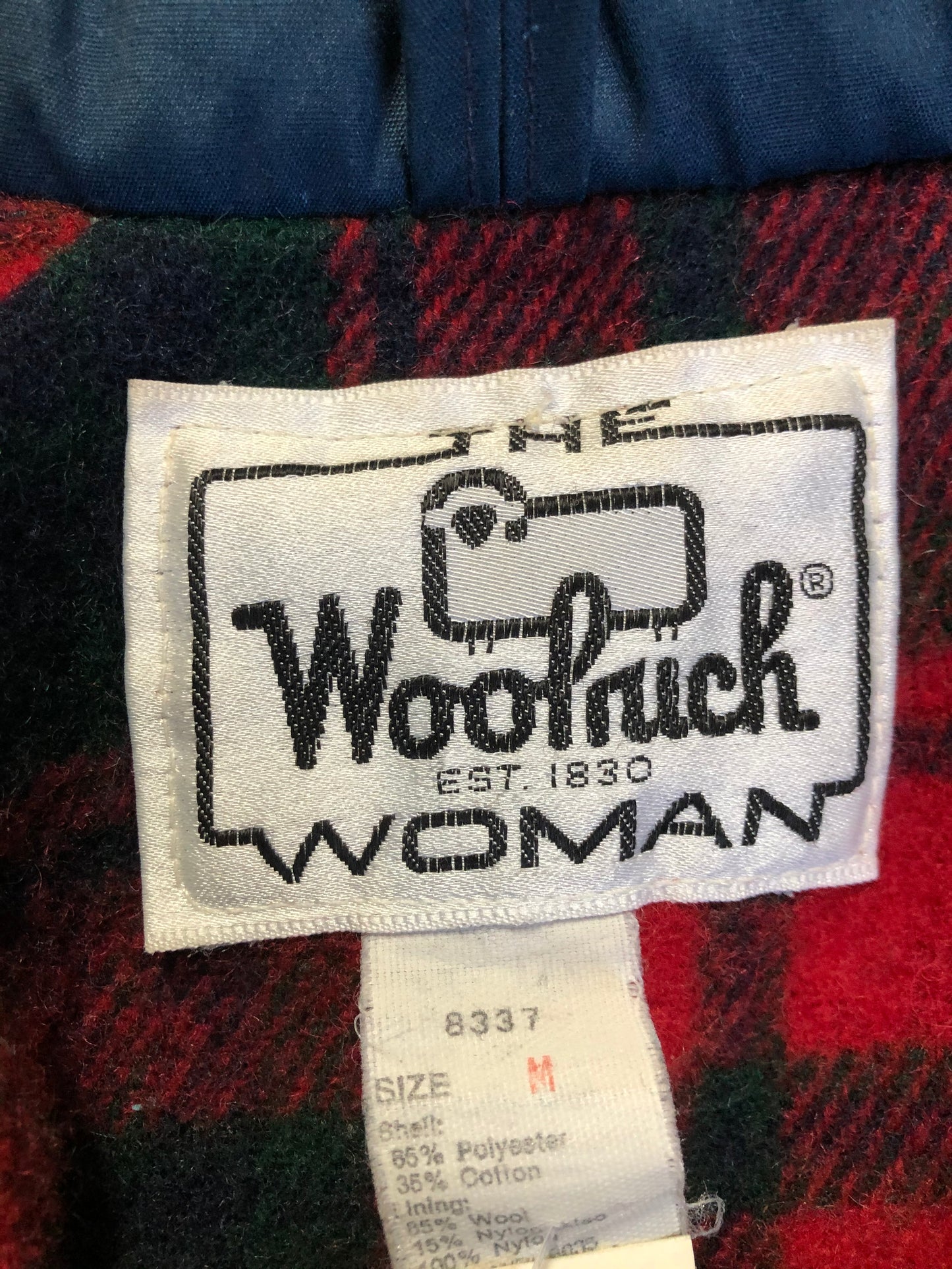 Kingspier Vintage - Woolrich Woman navy jacket with raglan sleeves, hood, zipper, snap closures with sheep logo, two flap pockets, drawstring at waist and red plaid wool lining. Made in the USA. Size medium.