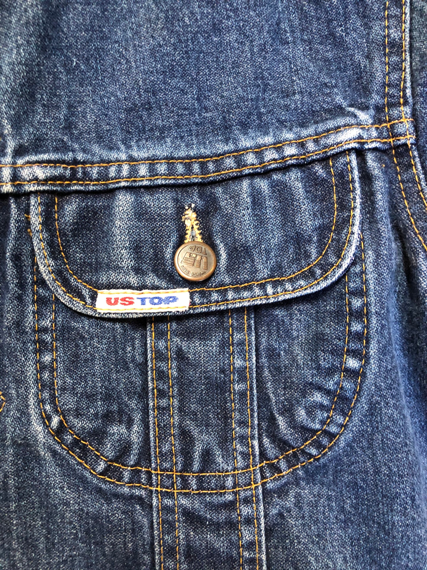 Kingspier Vintage - US Top denim jacket in a medium wash with button closures, two flap pockets on the chest, gold stitching with a unique stitch design down the center front.
