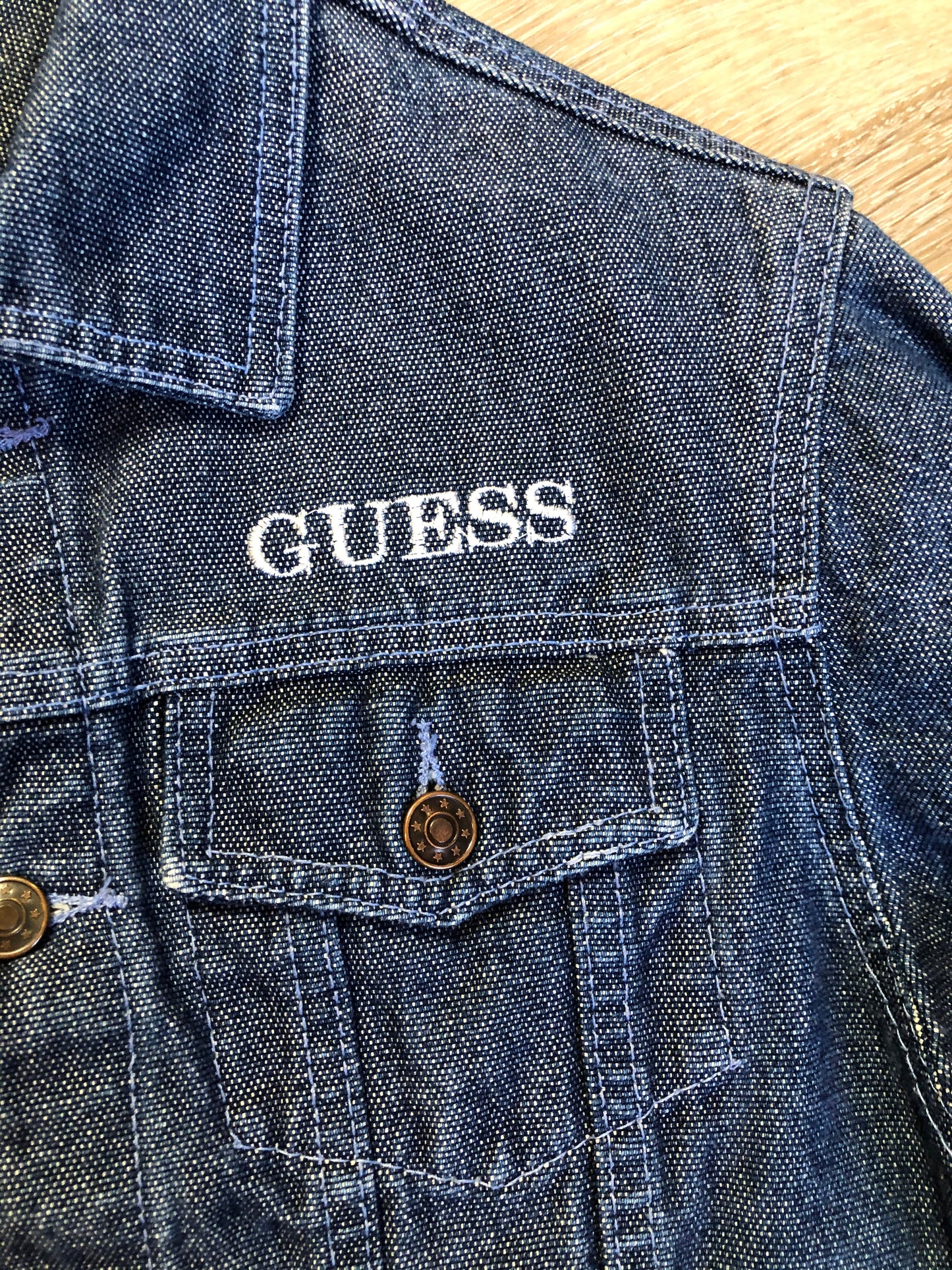 Kingspier Vintage - Guess ‘Georges Marciano’ denim jacket in a medium wash. This jacket features lavender stitching, button closures, two vertical pockets, two flap pockets on the chest and inside pockets. Made in the USA. Size small (fits very small).