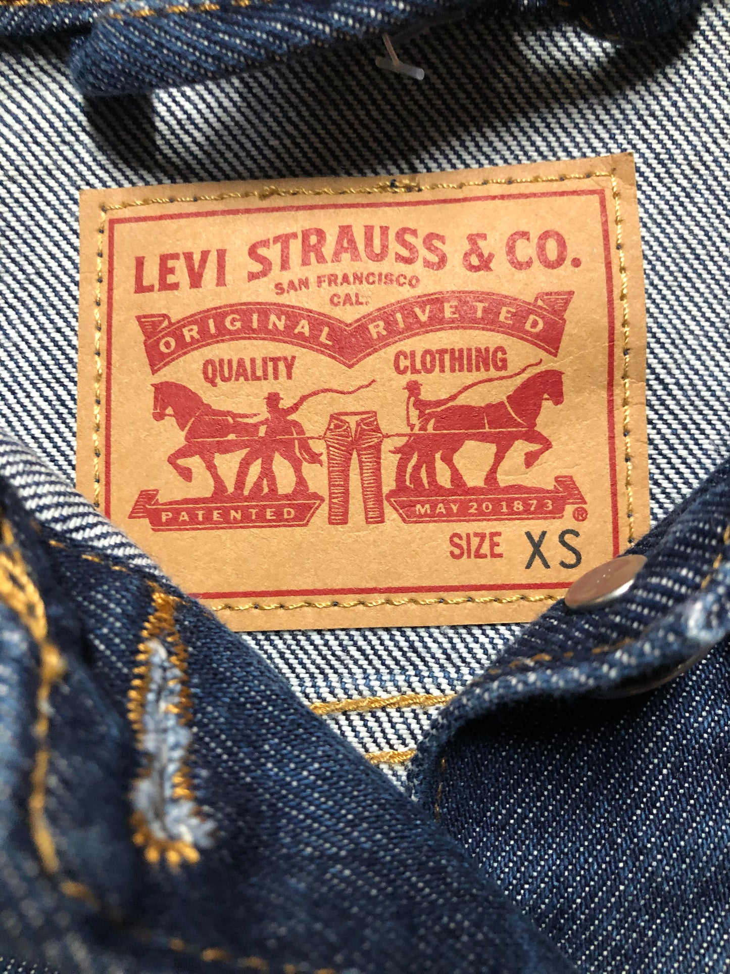 Kingspier Vintage - Levi’s Original Trucker Jacket in a medium wash denim with Canada leaf patch on the left shoulder, button closures, two vertical pockets and two flap pockets on the chest. Size XS.