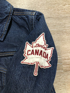 Kingspier Vintage - Levi’s Original Trucker Jacket in a medium wash denim with Canada leaf patch on the left shoulder, button closures, two vertical pockets and two flap pockets on the chest. Size XS.