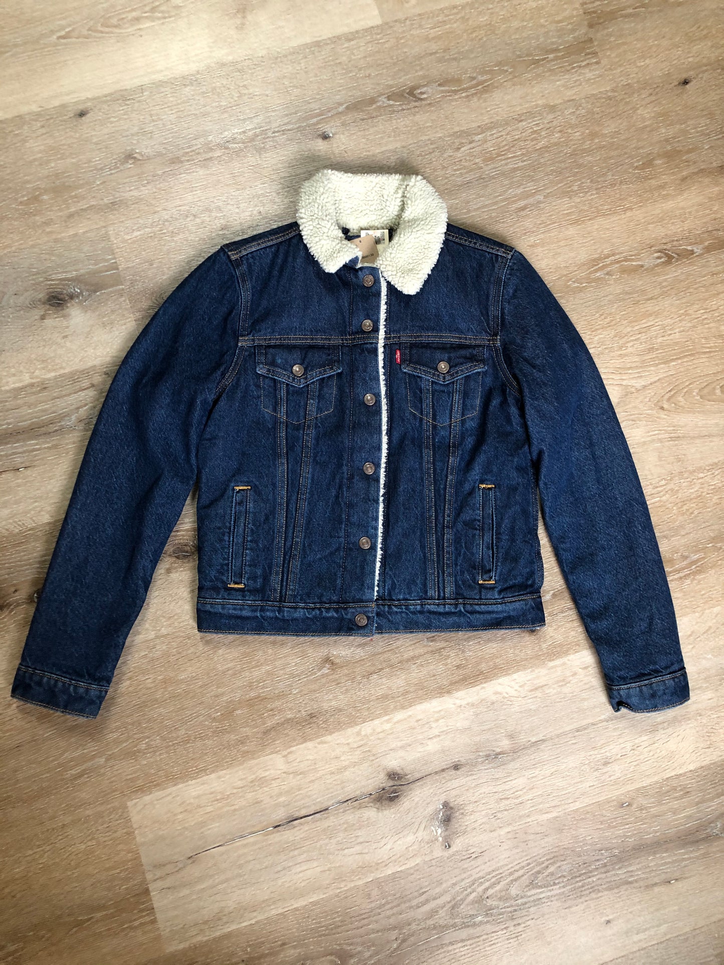 Kingspier Vintage - Levi’s denim sherpa trucker jacket in a medium wash with faux fur lining, snap closures, vertical pockets and two flap pockets. Size small.