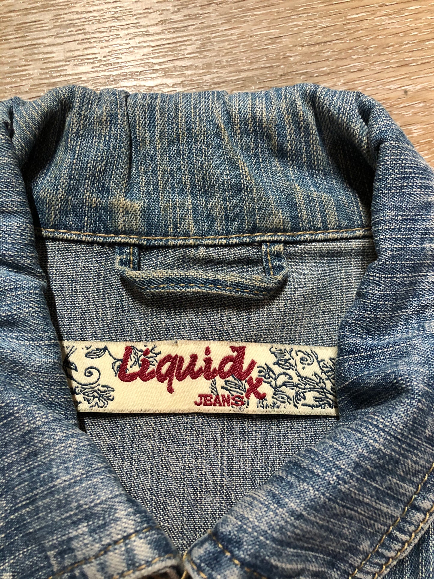 Kingspier Vintage - Liquid Jeans denim jacket in a light wash with buttons, hand warmer pockets and flap pockets on the chest. Size small.