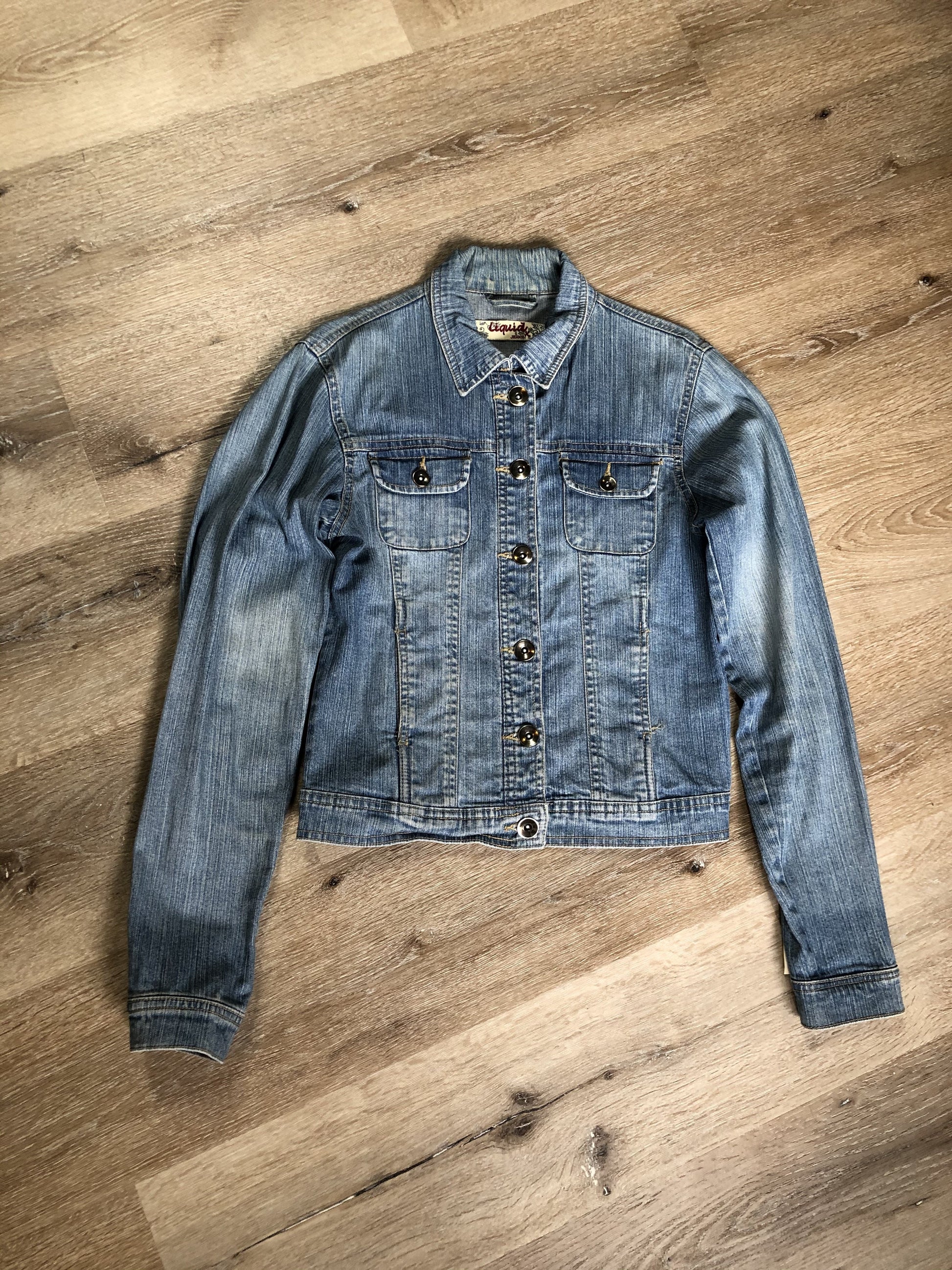 Kingspier Vintage - Liquid Jeans denim jacket in a light wash with buttons, hand warmer pockets and flap pockets on the chest. Size small.