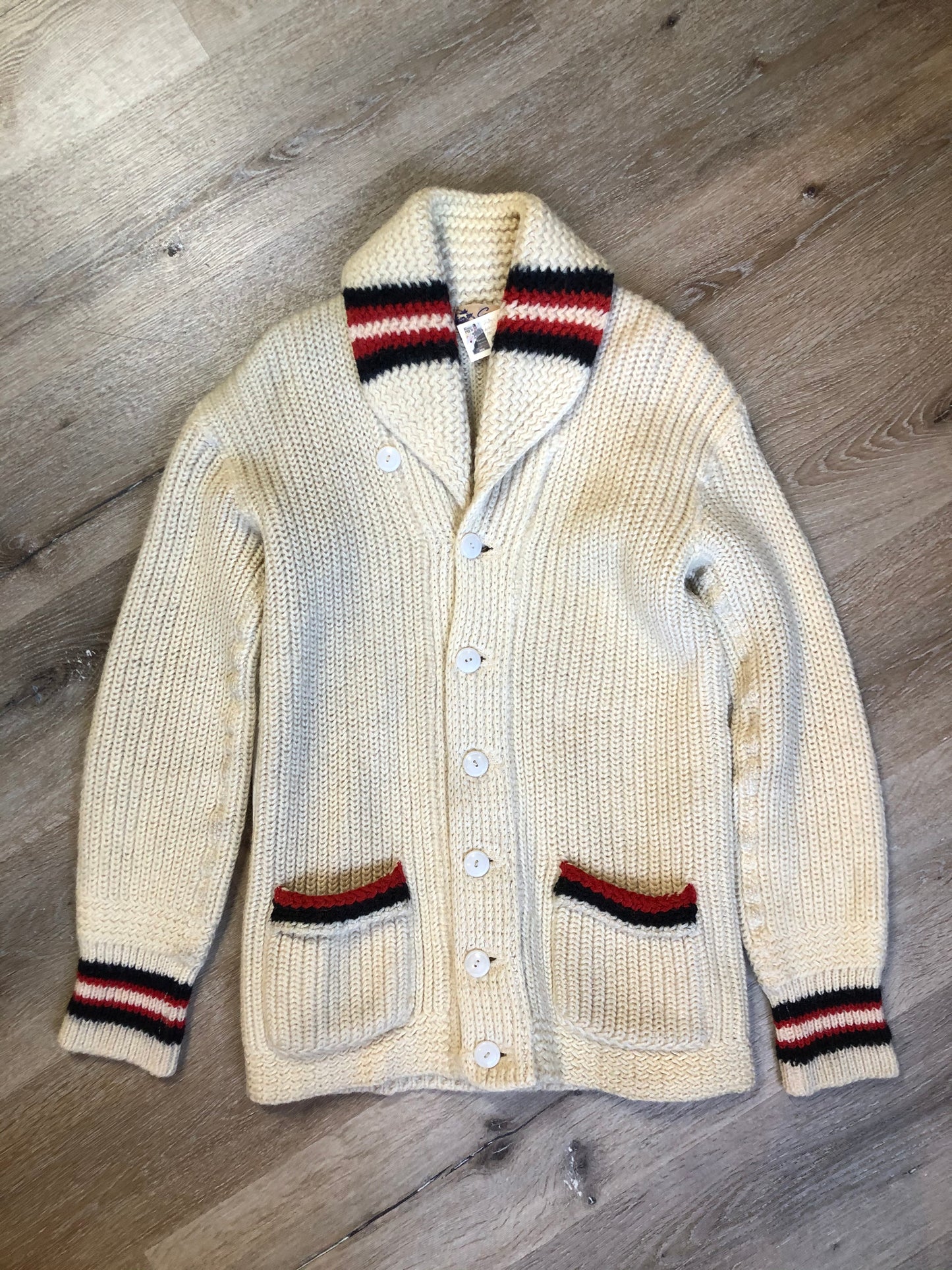Kingspier Vintage - Curl-Rite by Rice-Knit Sportswear 1950’s curing sweater in cream with red and black strip details, shawl collar, button closures and pockets. 100% wool. Size medium. Made in Nova Scotia.
