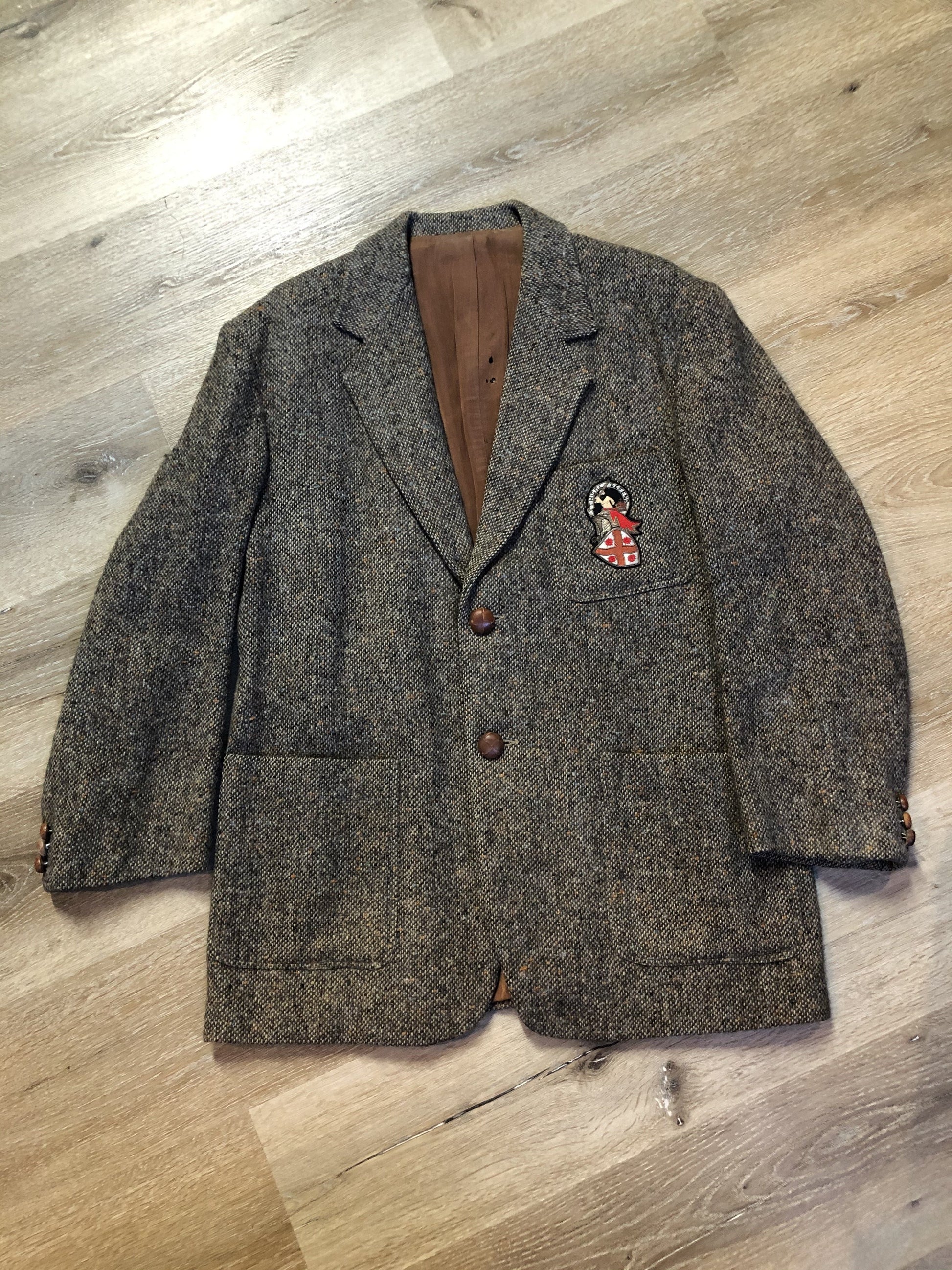 Kingspier Vintage - Donegal handwoven grey with blue and orange flecks 100% wool tweed jacket. This jacket is a two button, notch lapel with two patch pockets, a breast pocket and two inside pockets and a “this I defend” emblem embroidered on the chest. Made in Ireland.
