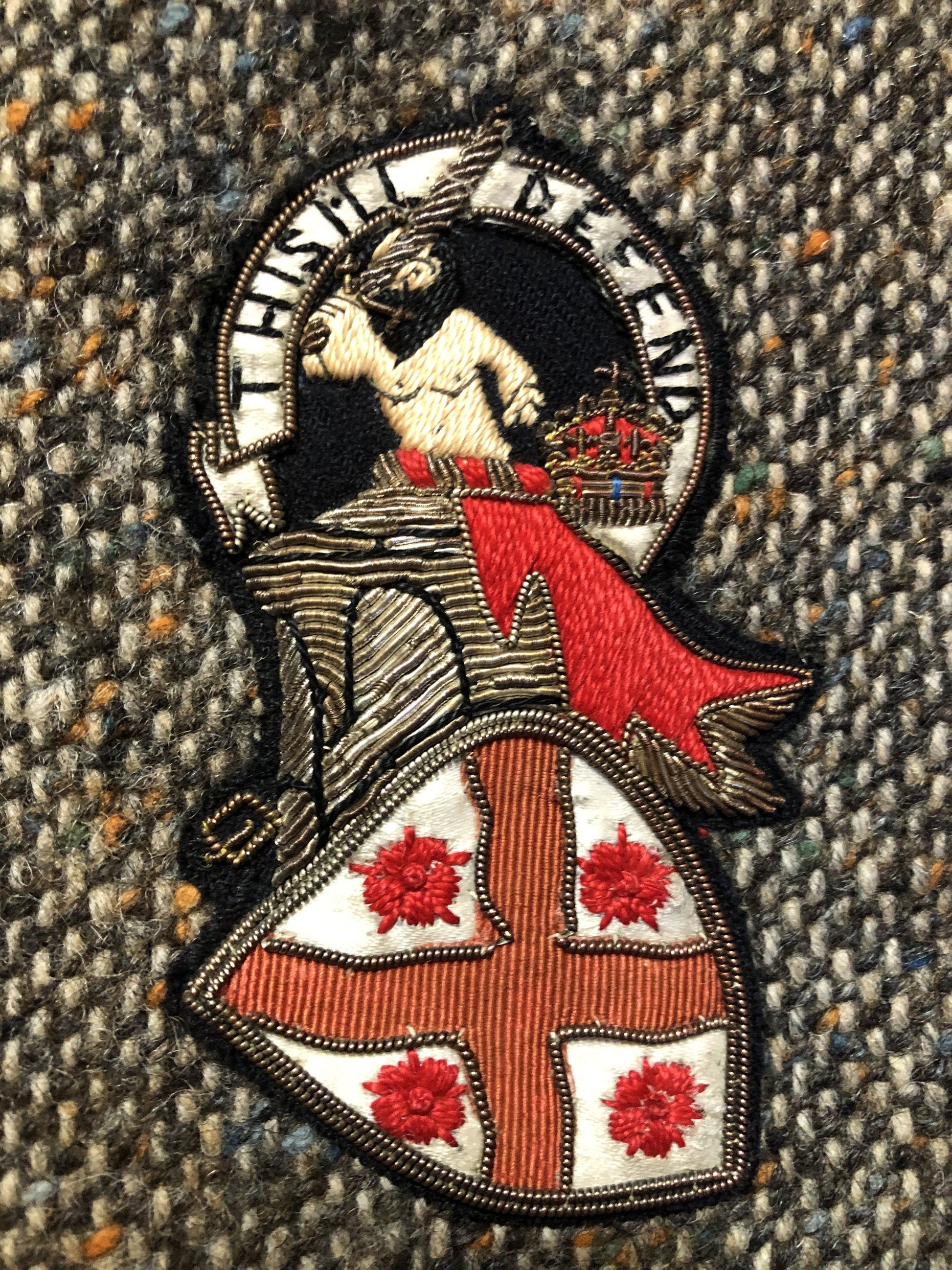 Kingspier Vintage - Donegal handwoven grey with blue and orange flecks 100% wool tweed jacket. This jacket is a two button, notch lapel with two patch pockets, a breast pocket and two inside pockets and a “this I defend” emblem embroidered on the chest. Made in Ireland.