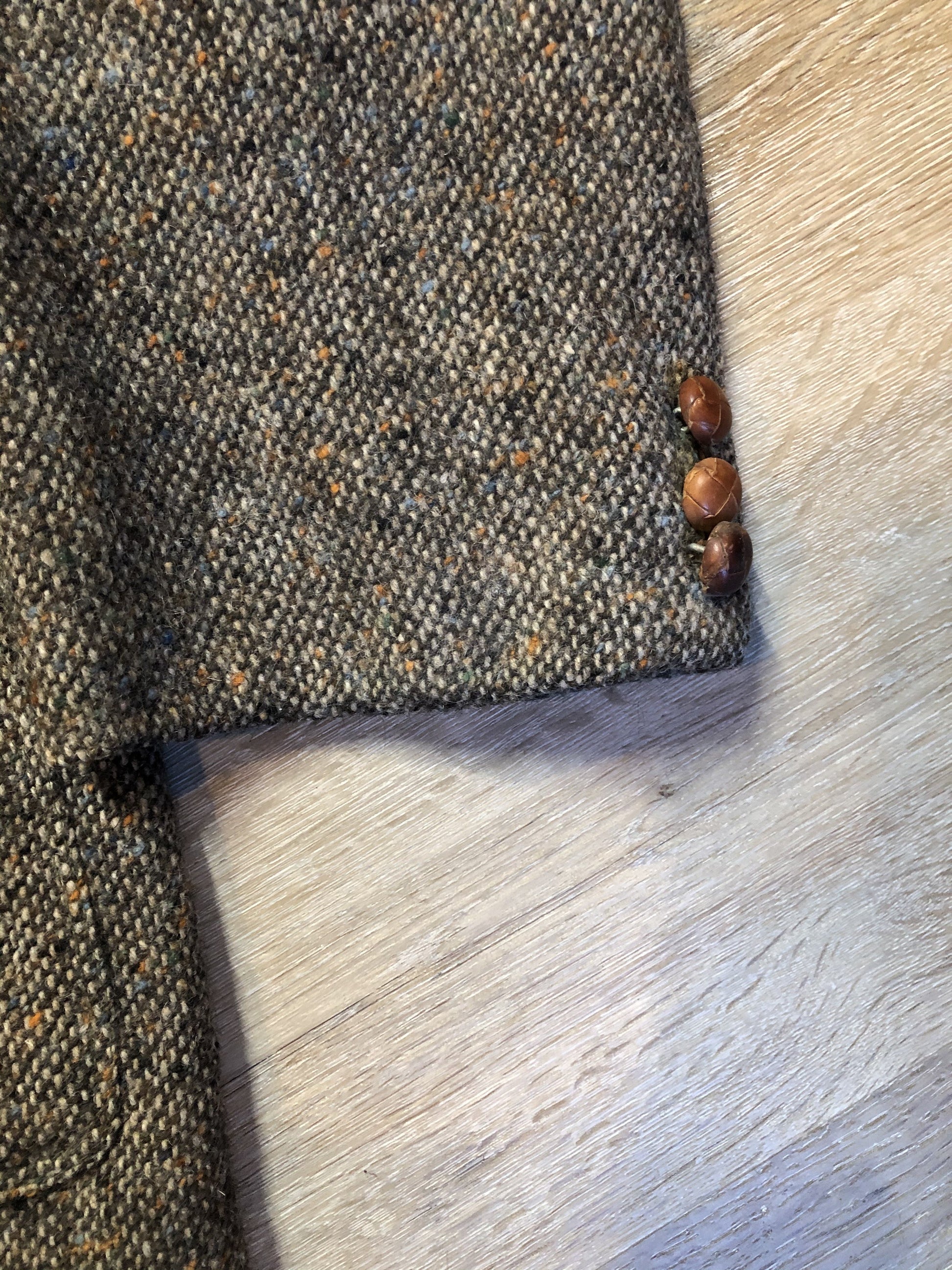 Kingspier Vintage - Donegal handwoven grey with blue and orange flecks 100% wool tweed jacket. This jacket is a two button, notch lapel with two patch pockets, a breast pocket and two inside pockets and a “this I defend” emblem embroidered on the chest. Made in Ireland.