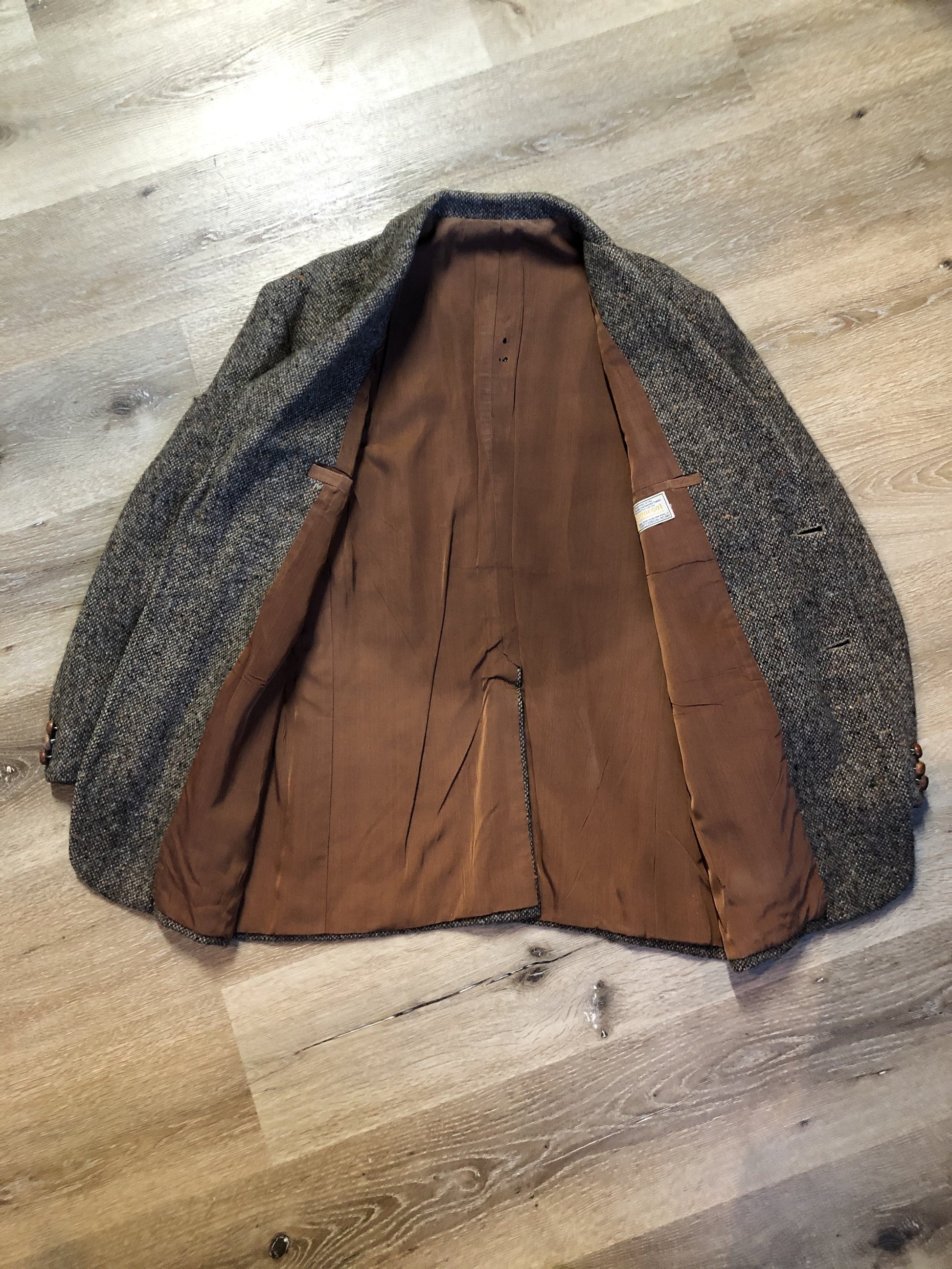 Kingspier Vintage - Donegal handwoven grey with blue and orange flecks 100% wool tweed jacket. This jacket is a two button, notch lapel with two patch pockets, a breast pocket and two inside pockets and a “this I defend” emblem embroidered on the chest. Made in Ireland.